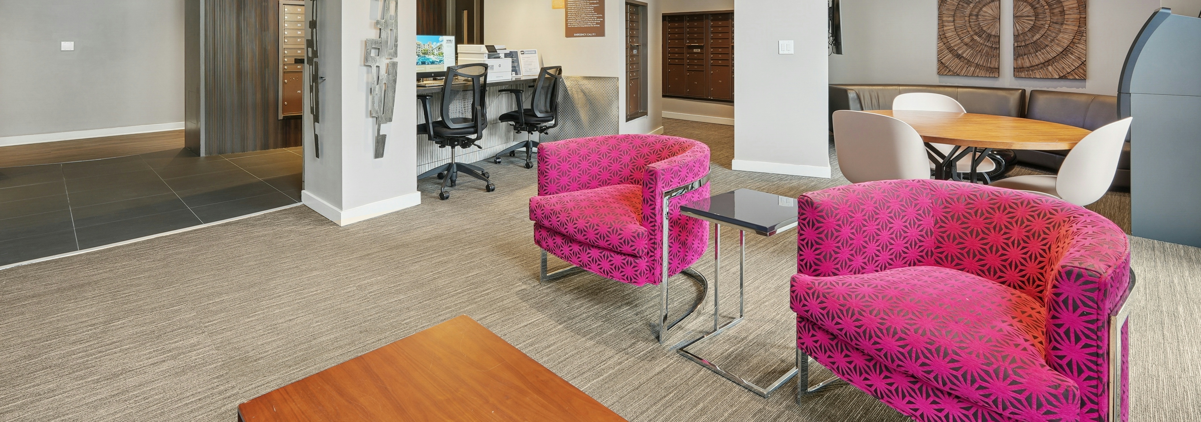 AMLI Dadeland apartments business center with a desktop computer and printer and multiple chairs and a view into the mailroom