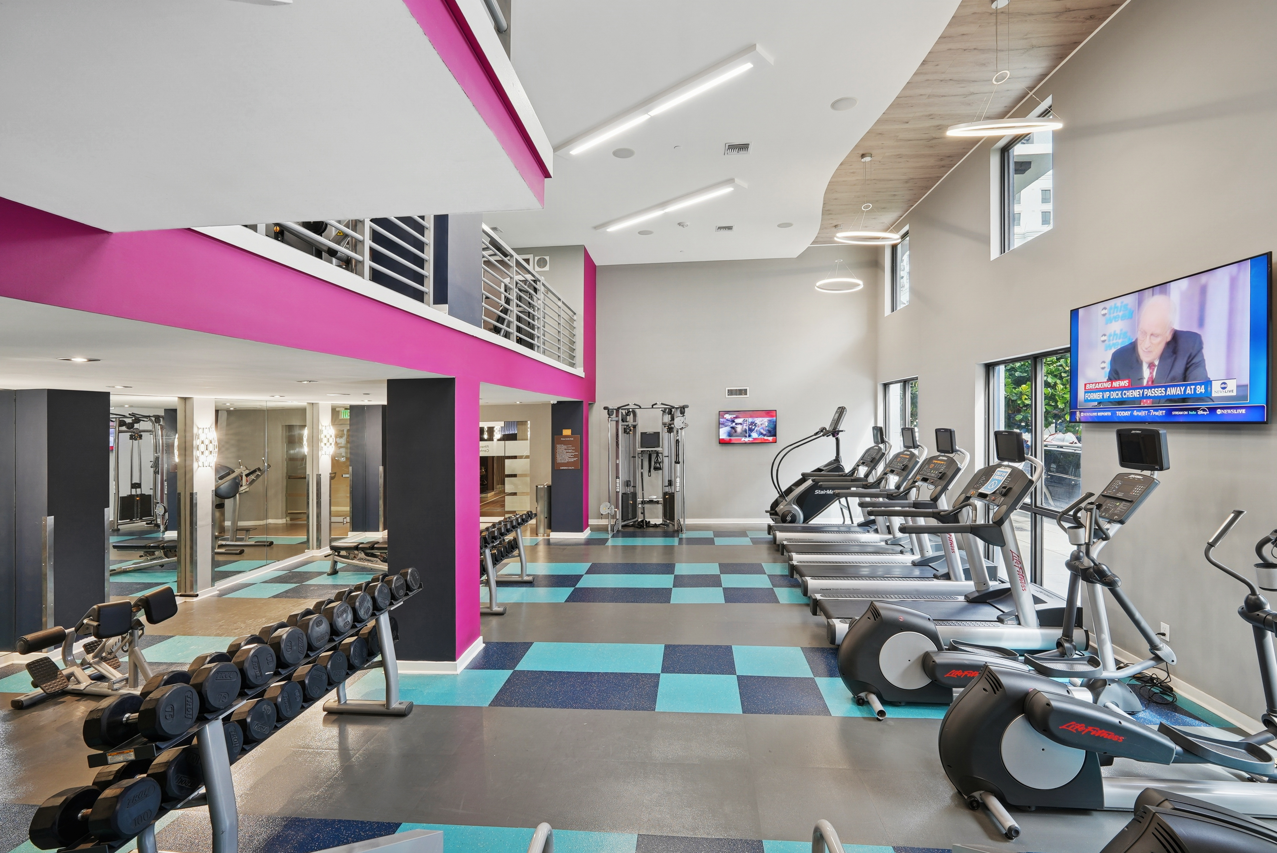 Interior view of a two story fitness center at AMLI Dadeland with cardio equipment and weights and a flat screen television