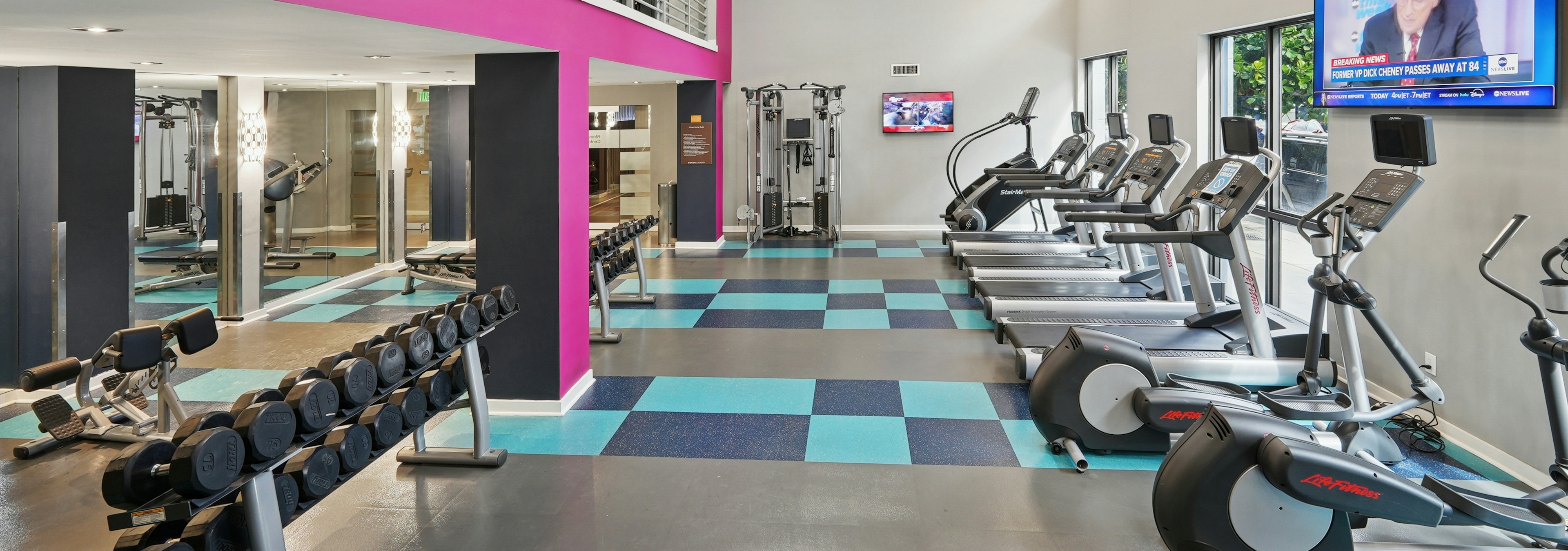 Interior view of a two story fitness center at AMLI Dadeland with cardio equipment and weights and a flat screen television