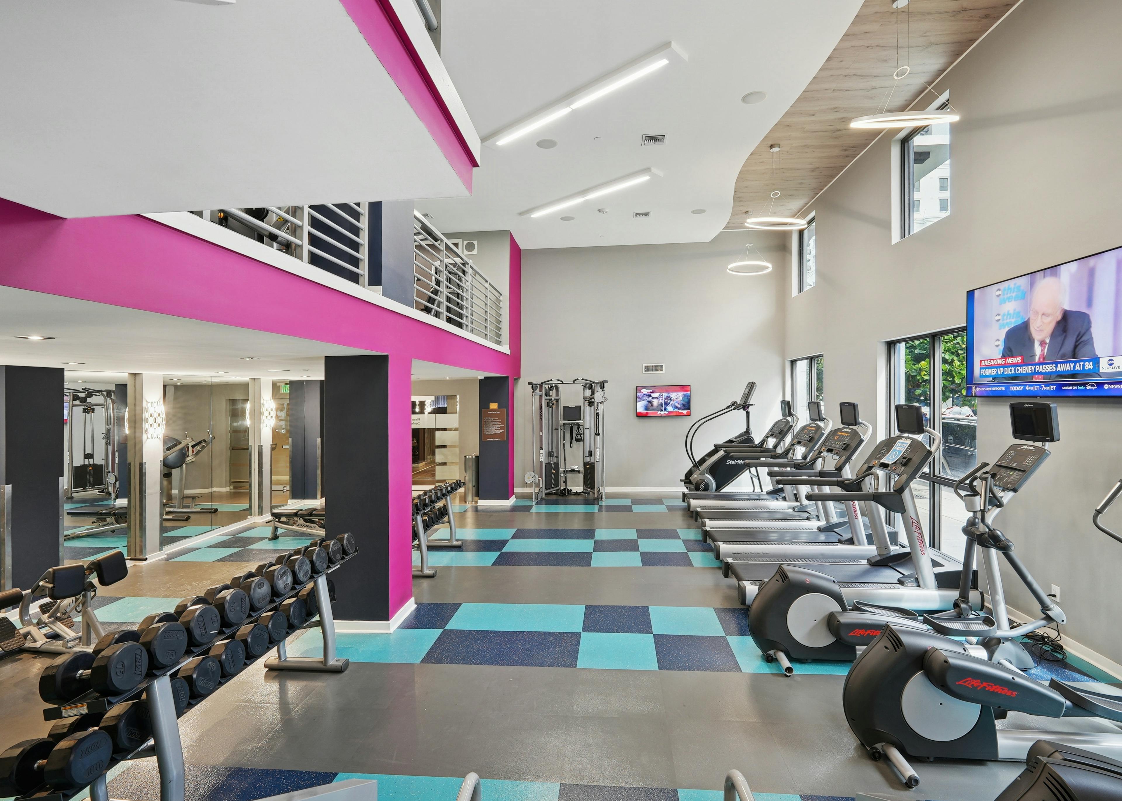 Interior view of a two story fitness center at AMLI Dadeland with cardio equipment and weights and a flat screen television