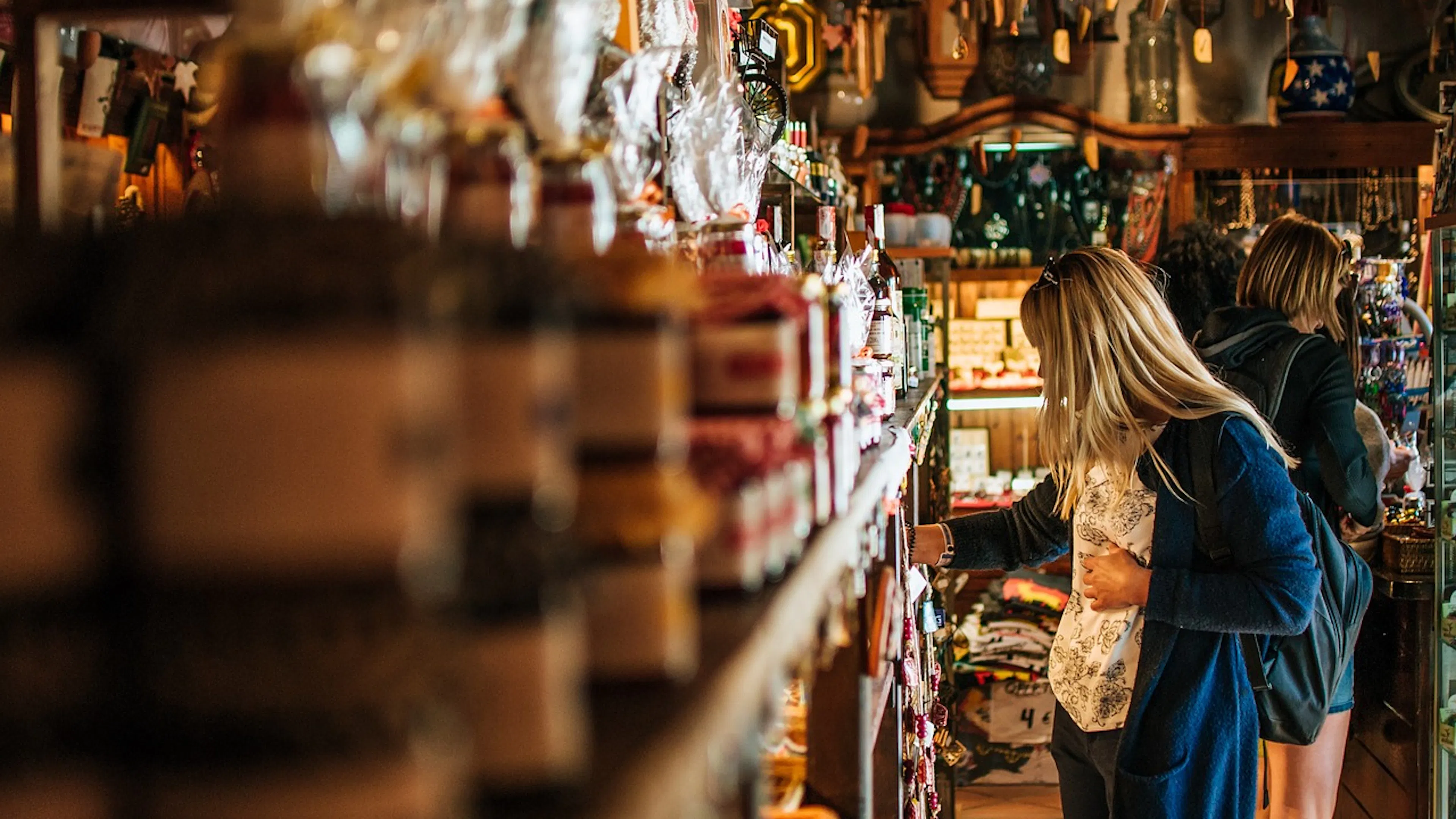 woman shopping in small store with cans and packages lining shelves