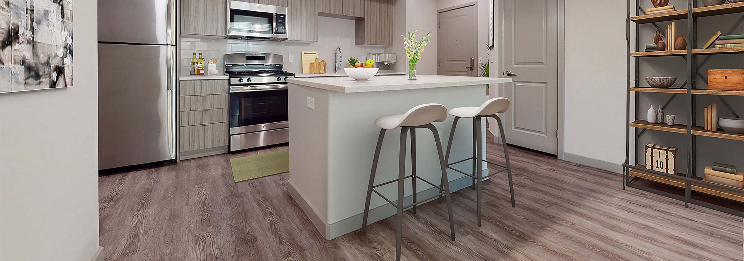 Open kitchen at AMLI Camarillo apartments with island seating, pendant lights, stainless steel appliances and modern wood cabinetry.