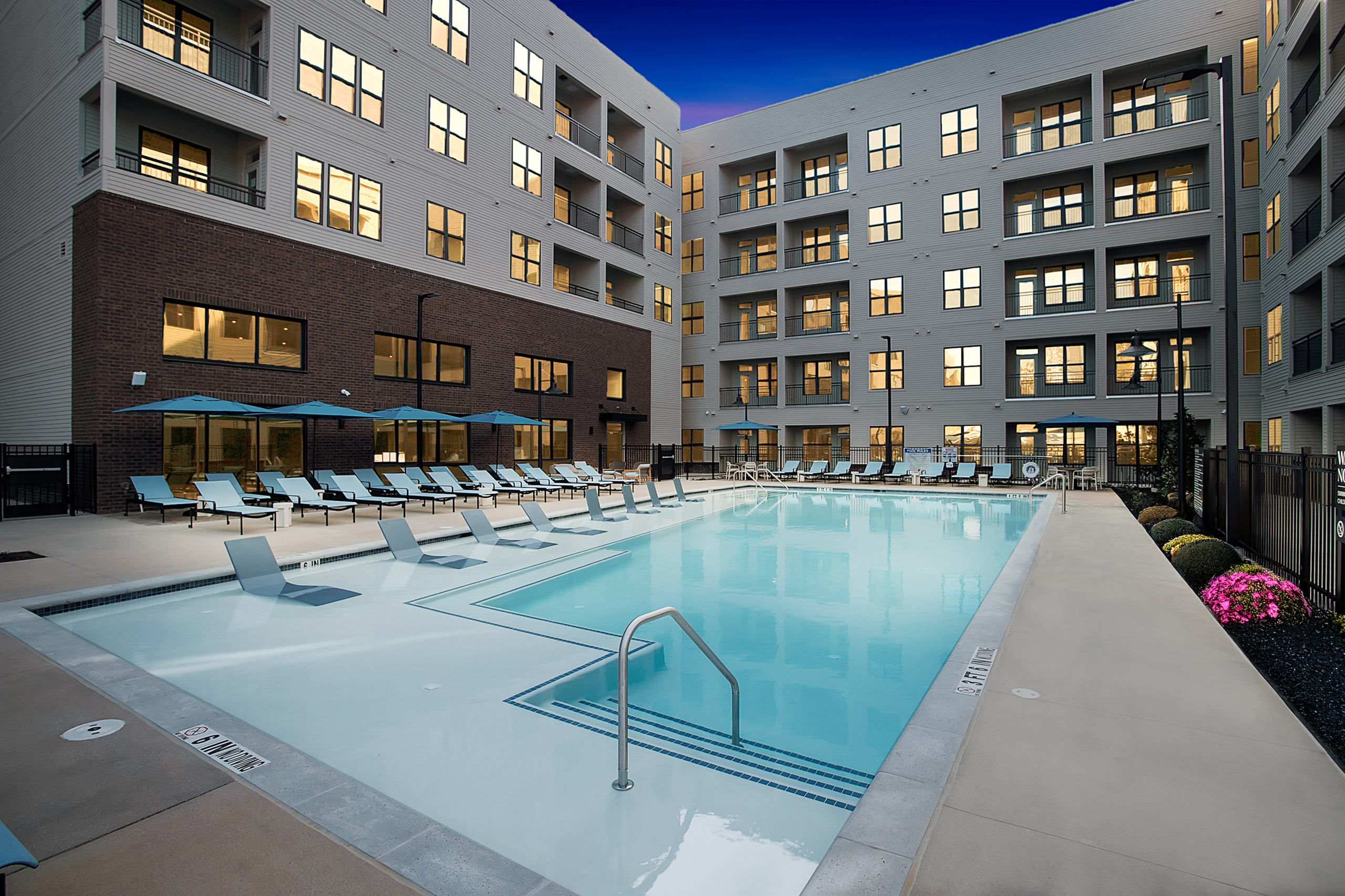 Swimming pool at AMLI Brookhaven with lounge chairs and umbrellas.