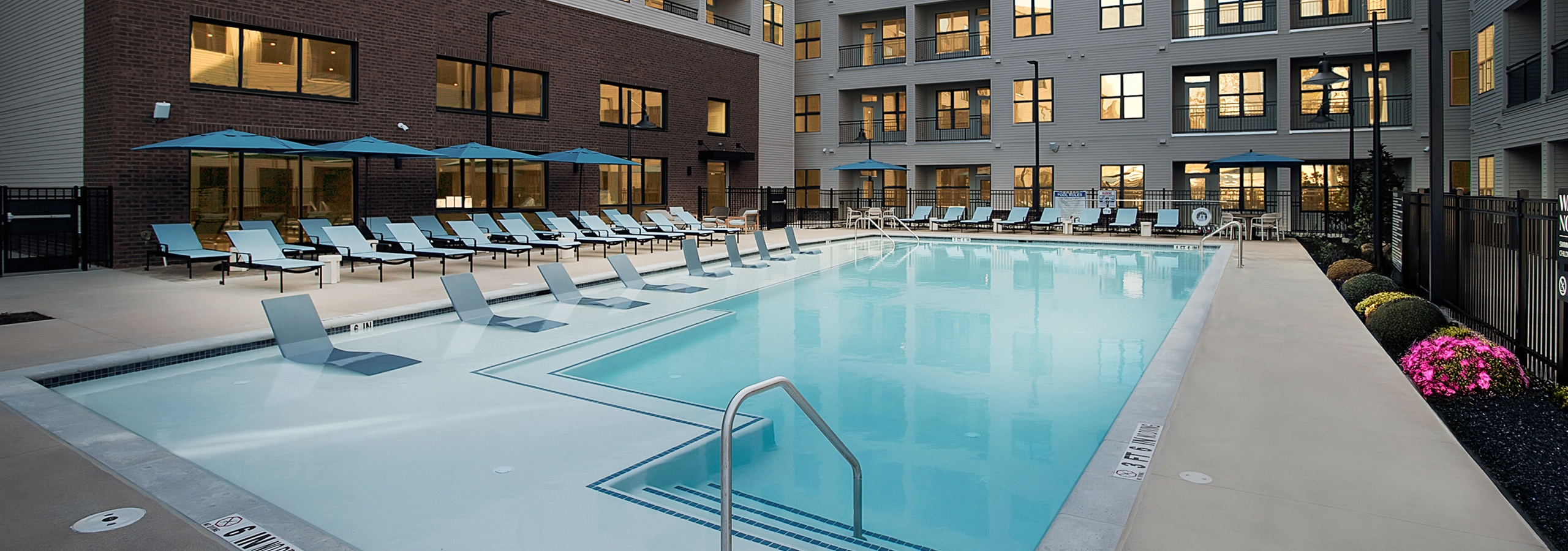 Swimming pool at AMLI Brookhaven with lounge chairs and umbrellas.