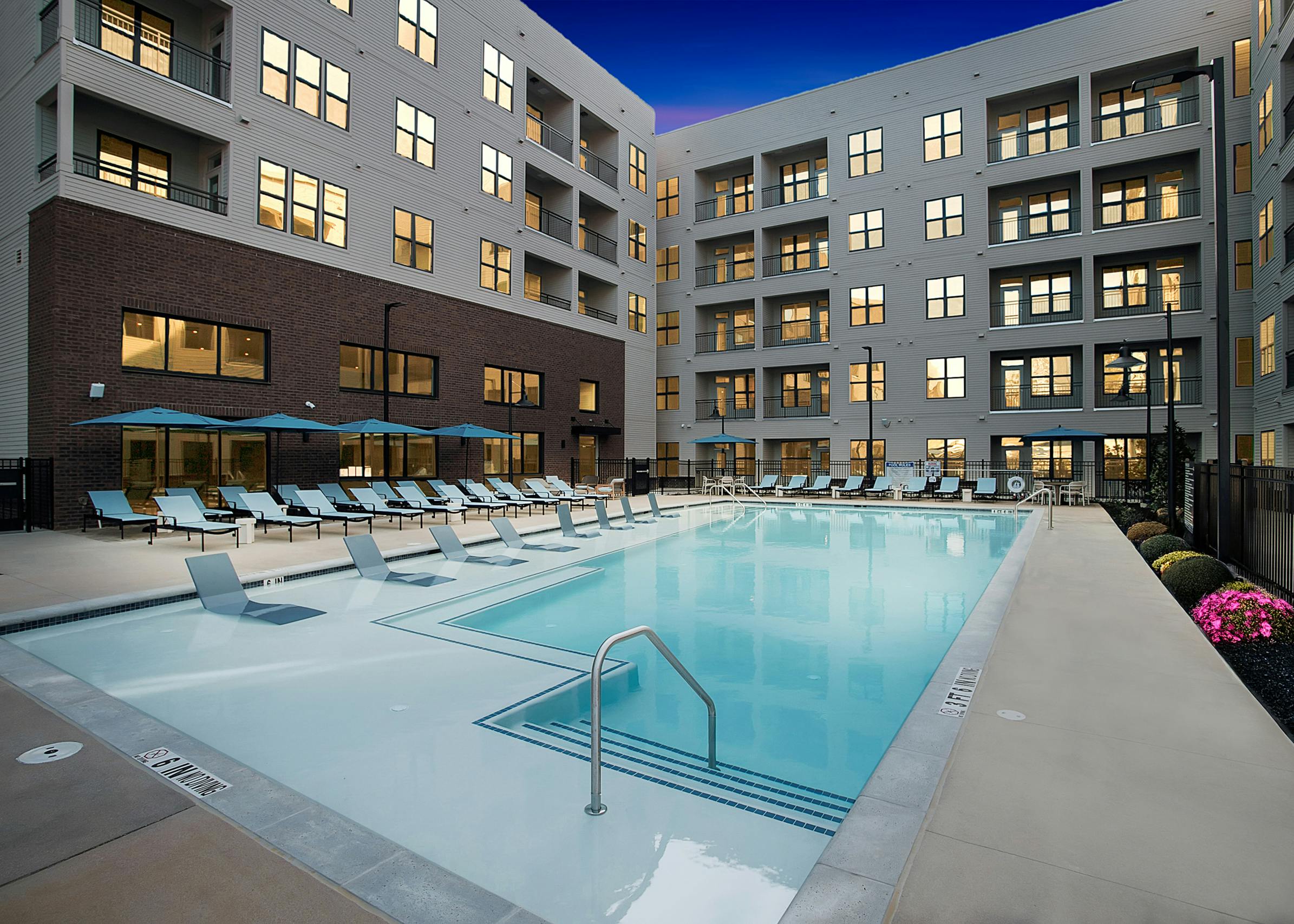 Swimming pool at AMLI Brookhaven with lounge chairs and umbrellas.