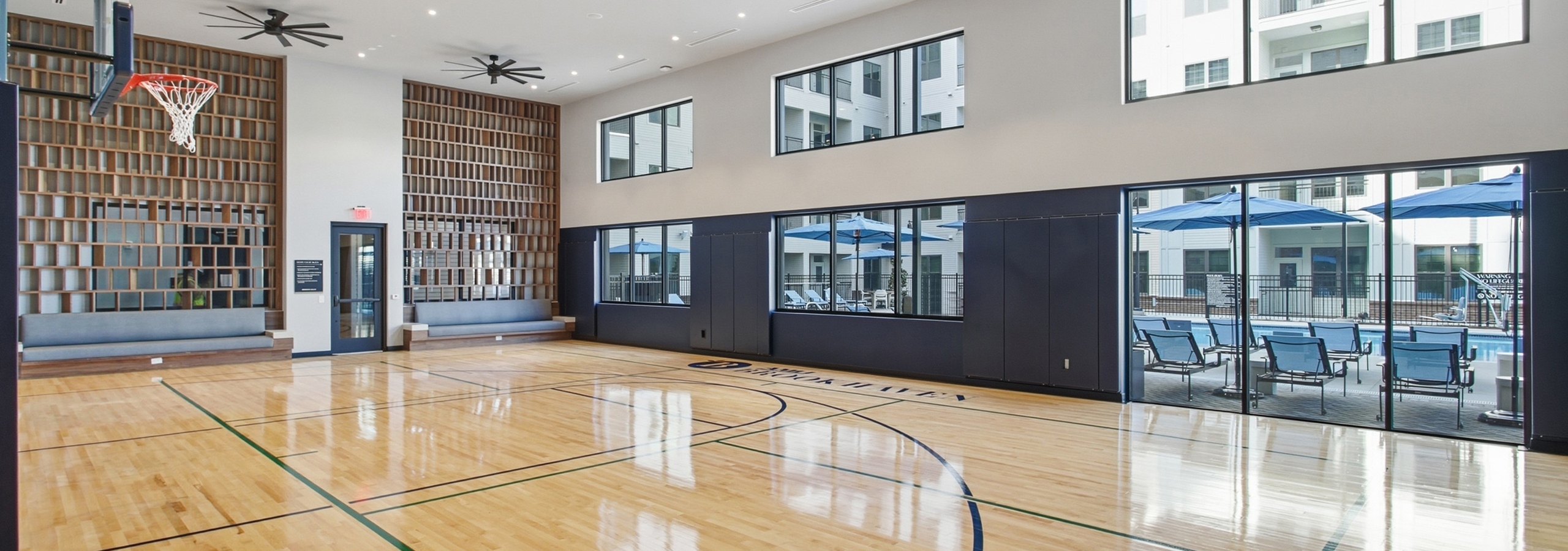 Indoor sport court with basketball hoop overlooking a swimming pool deck at AMLI Brookhaven.