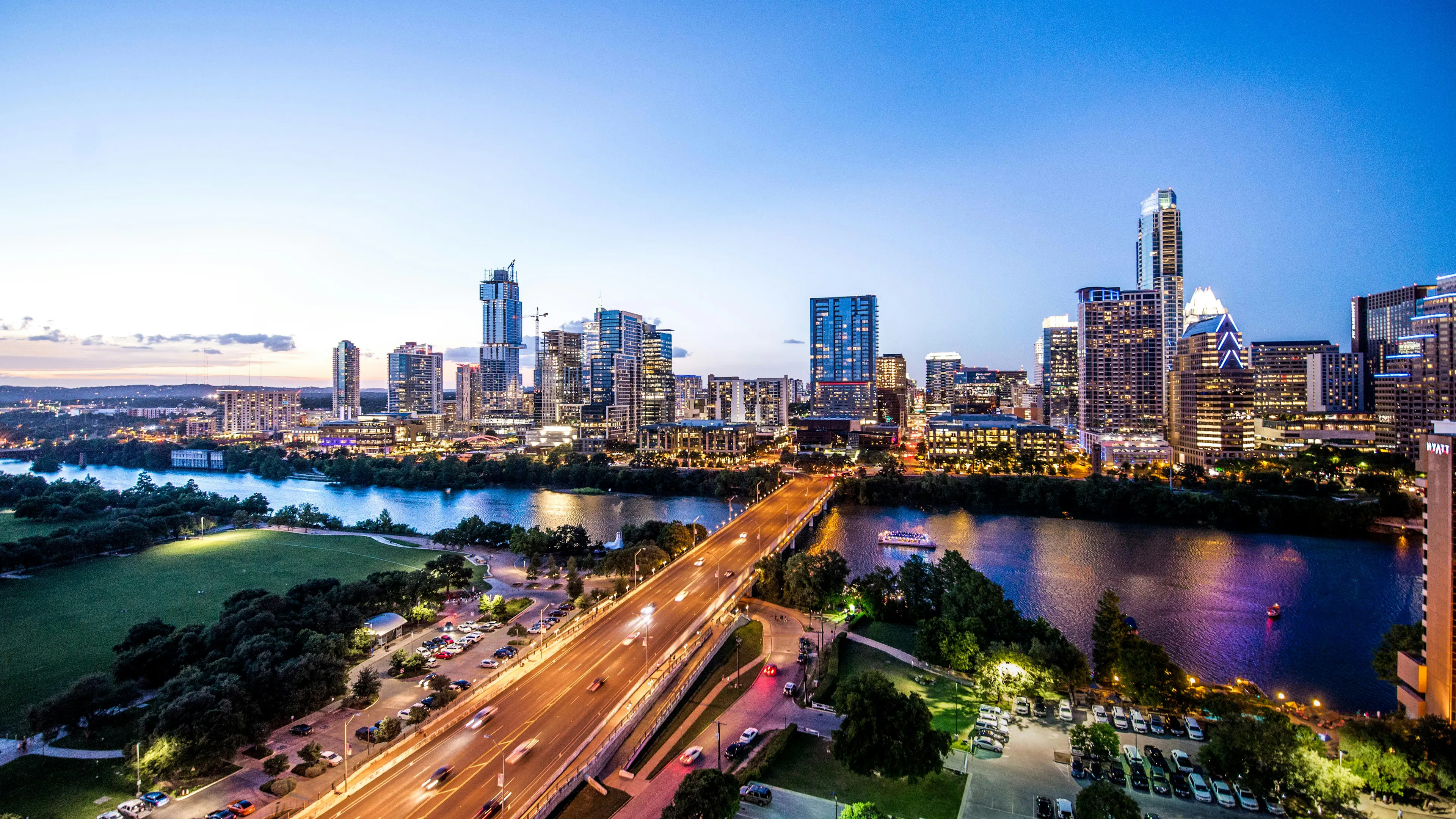 A stunning twilight view of the Austin, Texas skyline and Congress Avenue Bridge reflecting over Lady Bird Lake at blue hour.