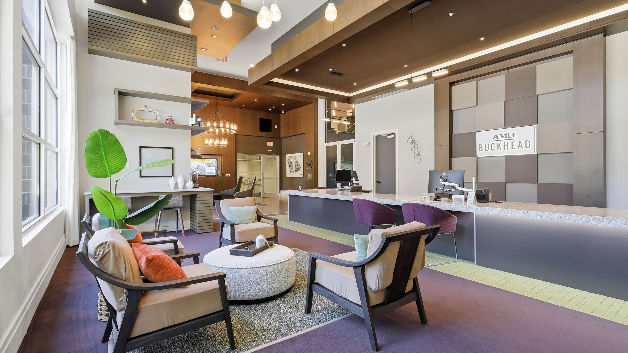 Leasing office at AMLI Buckhead apartments with carpeting throughout and vaulted ceilings with overhead light and front desk