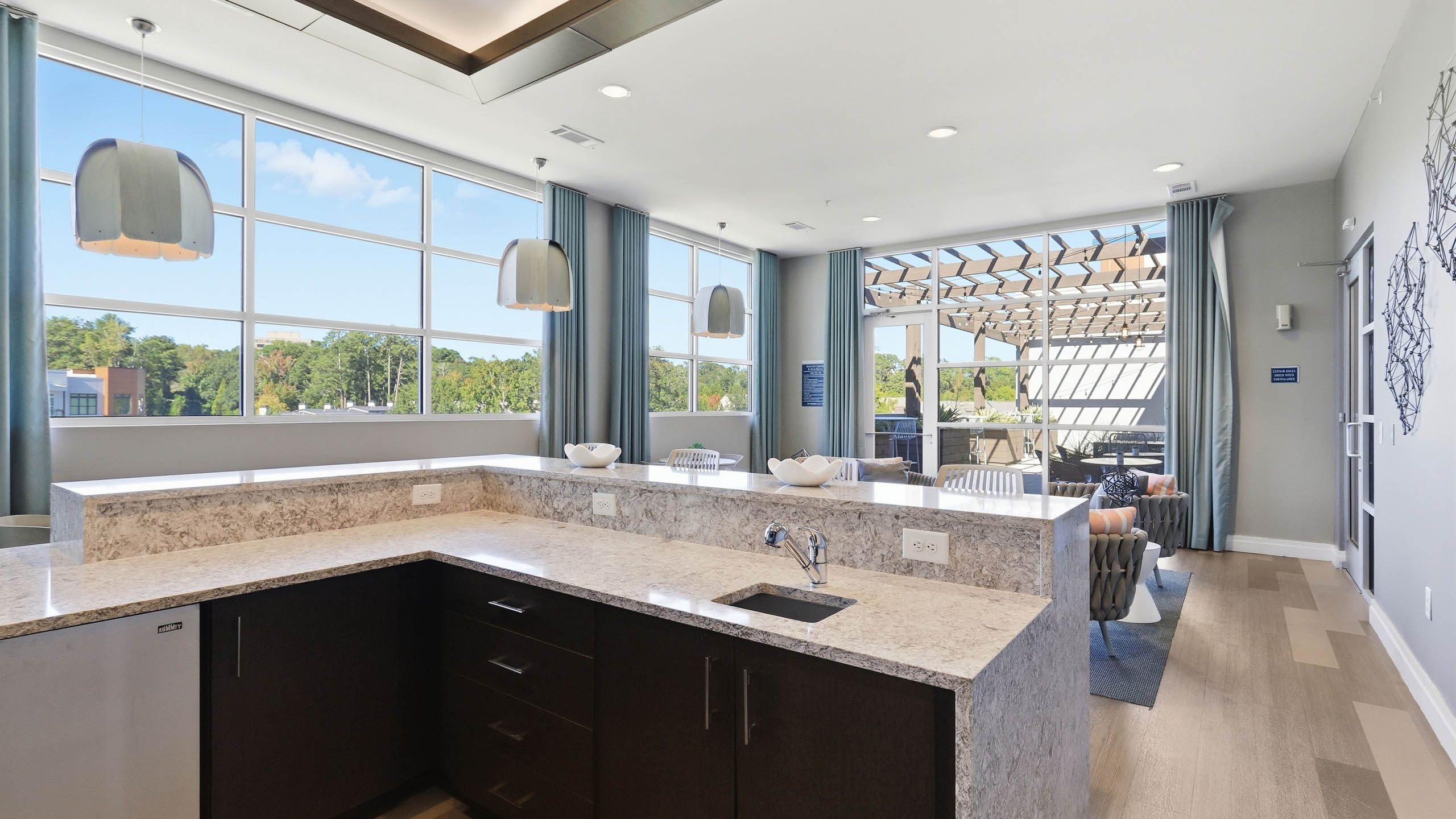 An indoor resident lounge at AMLI Buckhead apartments with a quartz kitchen countertop and sink with wooden drawers below