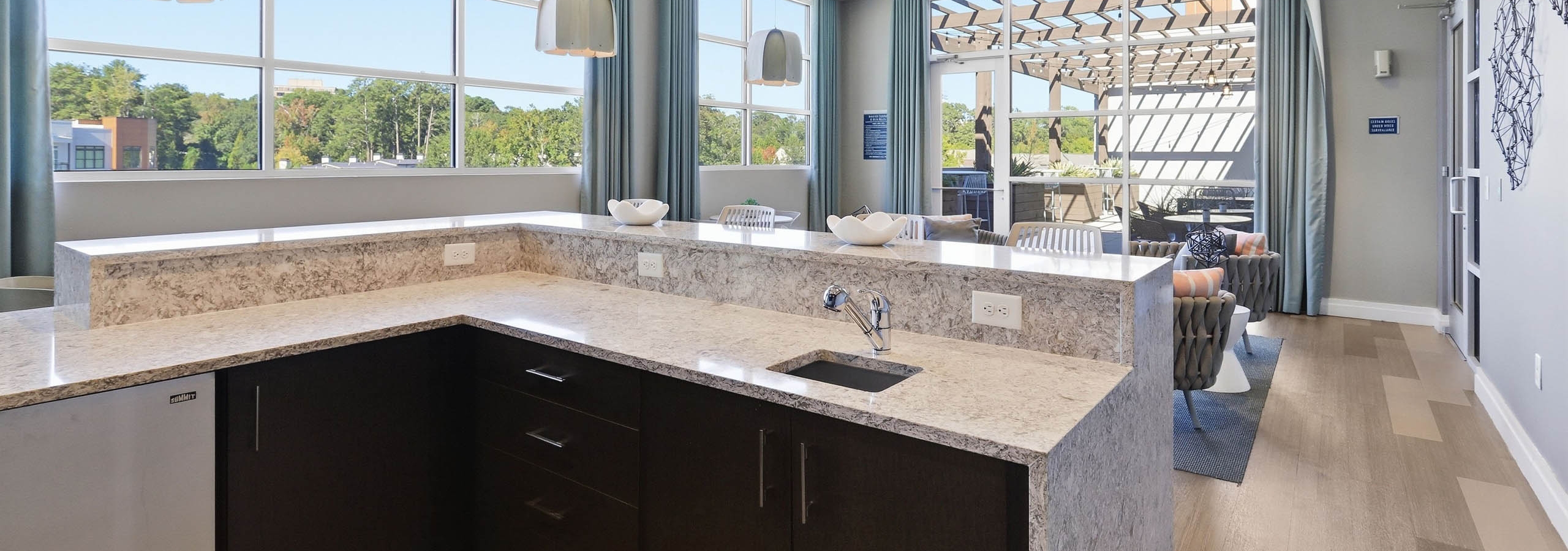 An indoor resident lounge at AMLI Buckhead apartments with a quartz kitchen countertop and sink with wooden drawers below