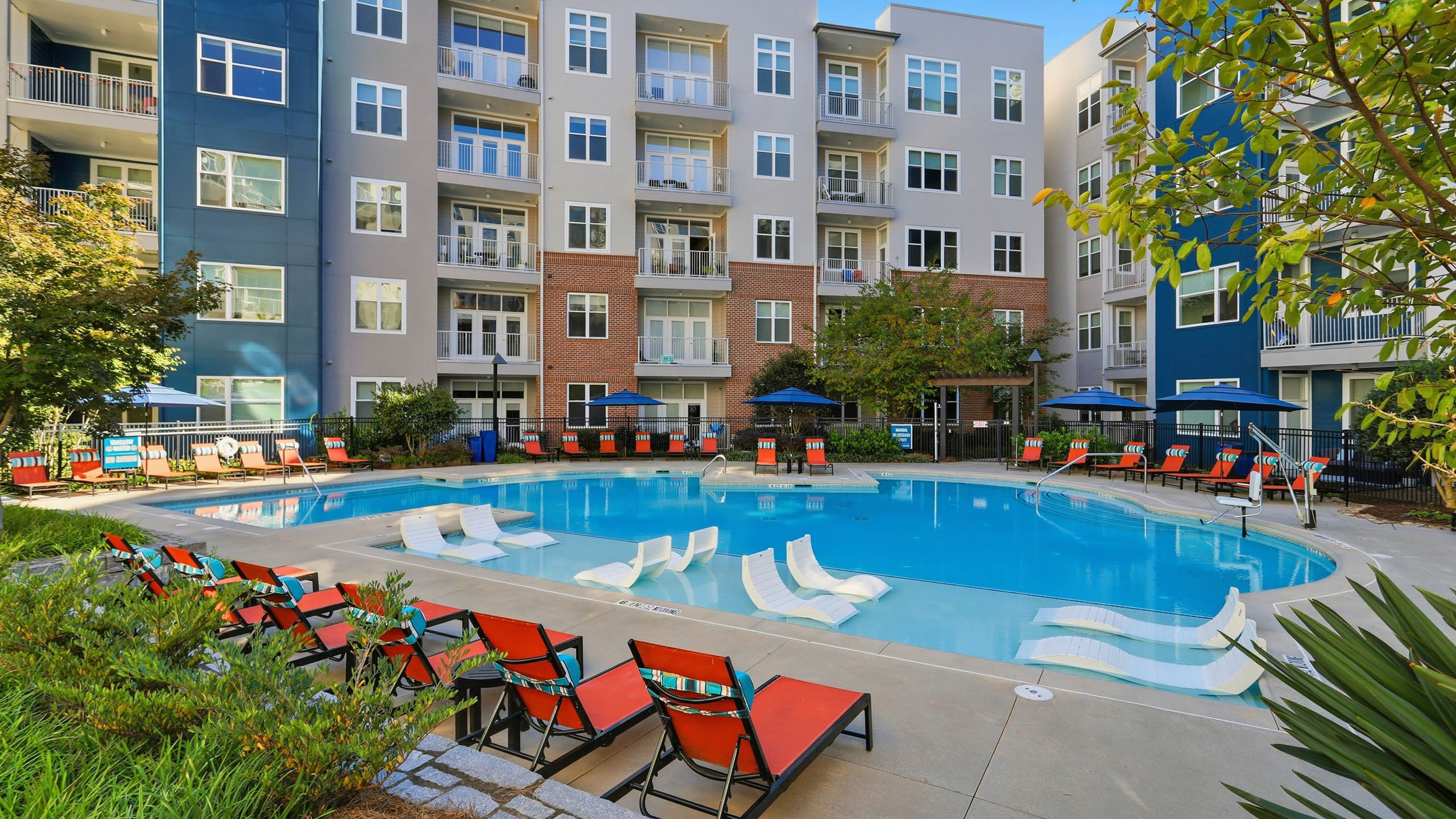 Swimming pool at AMLI Buckhead with reclining chairs on the deck as well as lounge chairs submerged in the shallow water