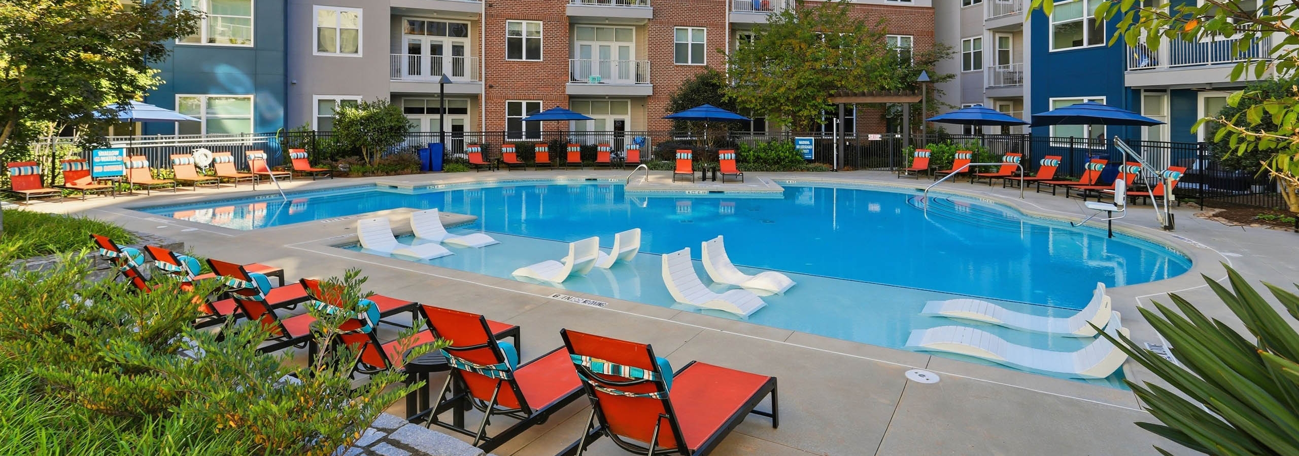 Swimming pool at AMLI Buckhead with reclining chairs on the deck as well as lounge chairs submerged in the shallow water