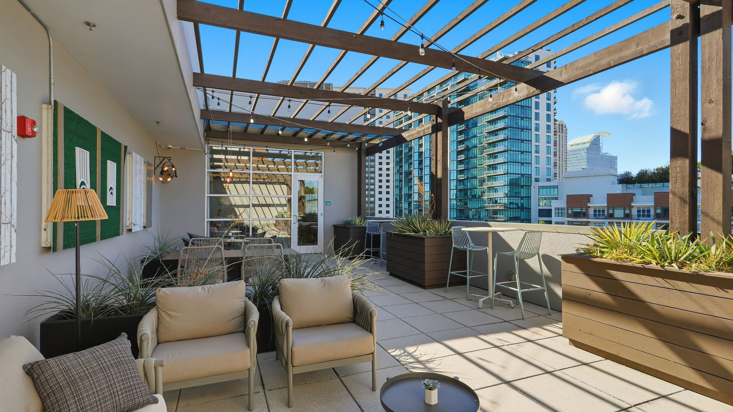 Exterior view of a rooftop lounge at AMLI Buckhead with couches and chairs and side tables with planter boxes and blue sky