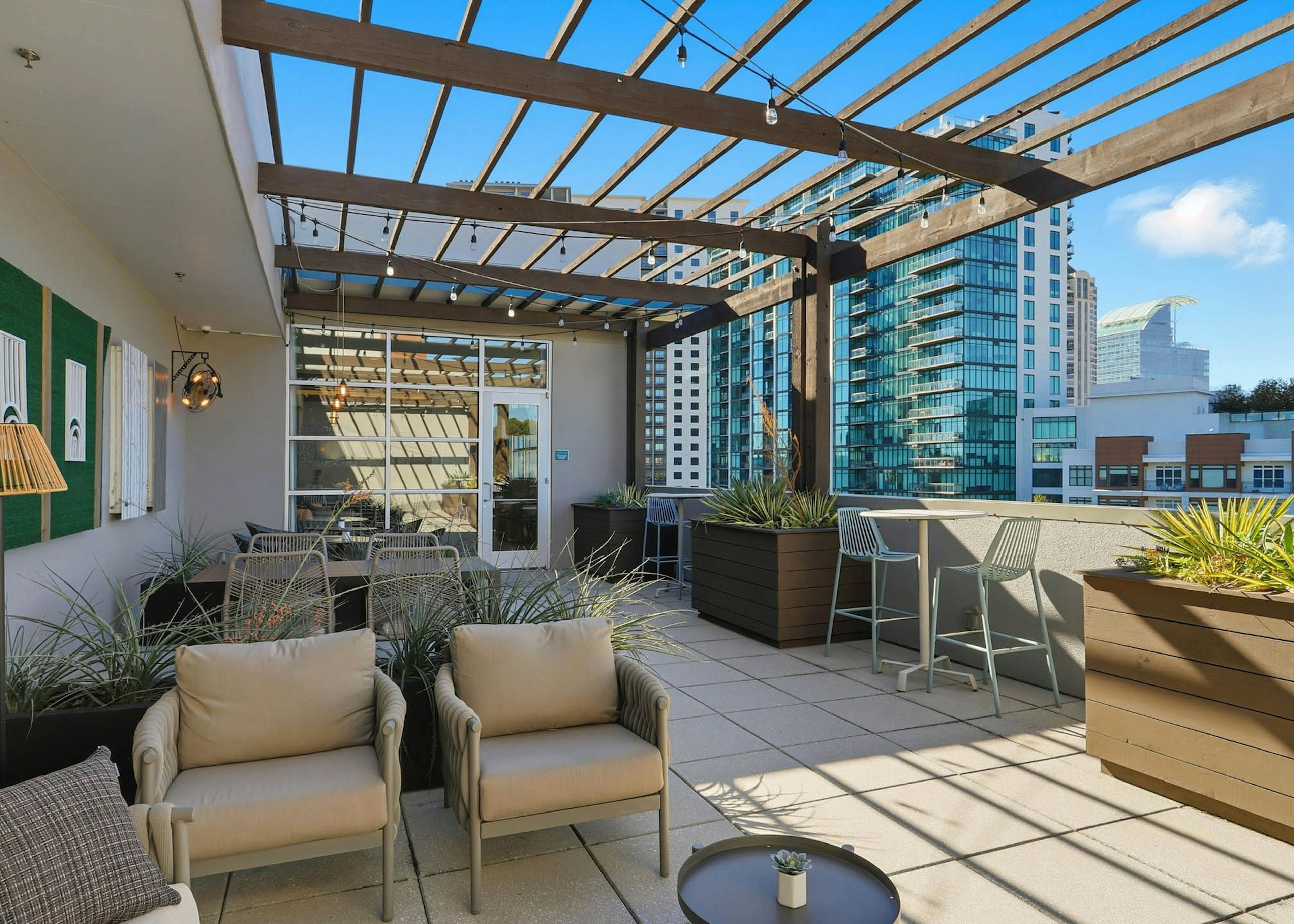 Exterior view of a rooftop lounge at AMLI Buckhead with couches and chairs and side tables with planter boxes and blue sky