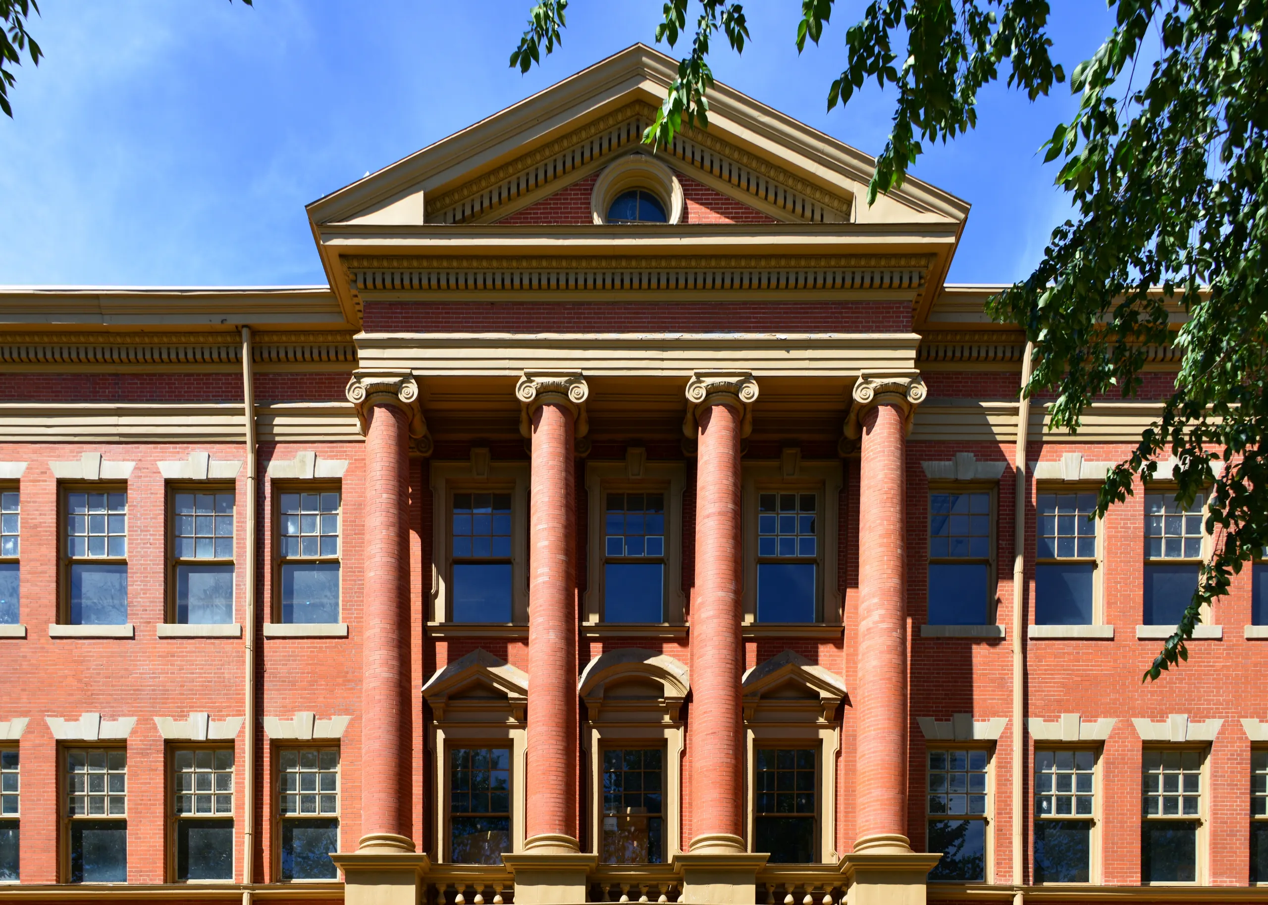 Exterior of the historic Evans School in Denver’s Golden Triangle, featuring red brick architecture and grand Ionic columns.