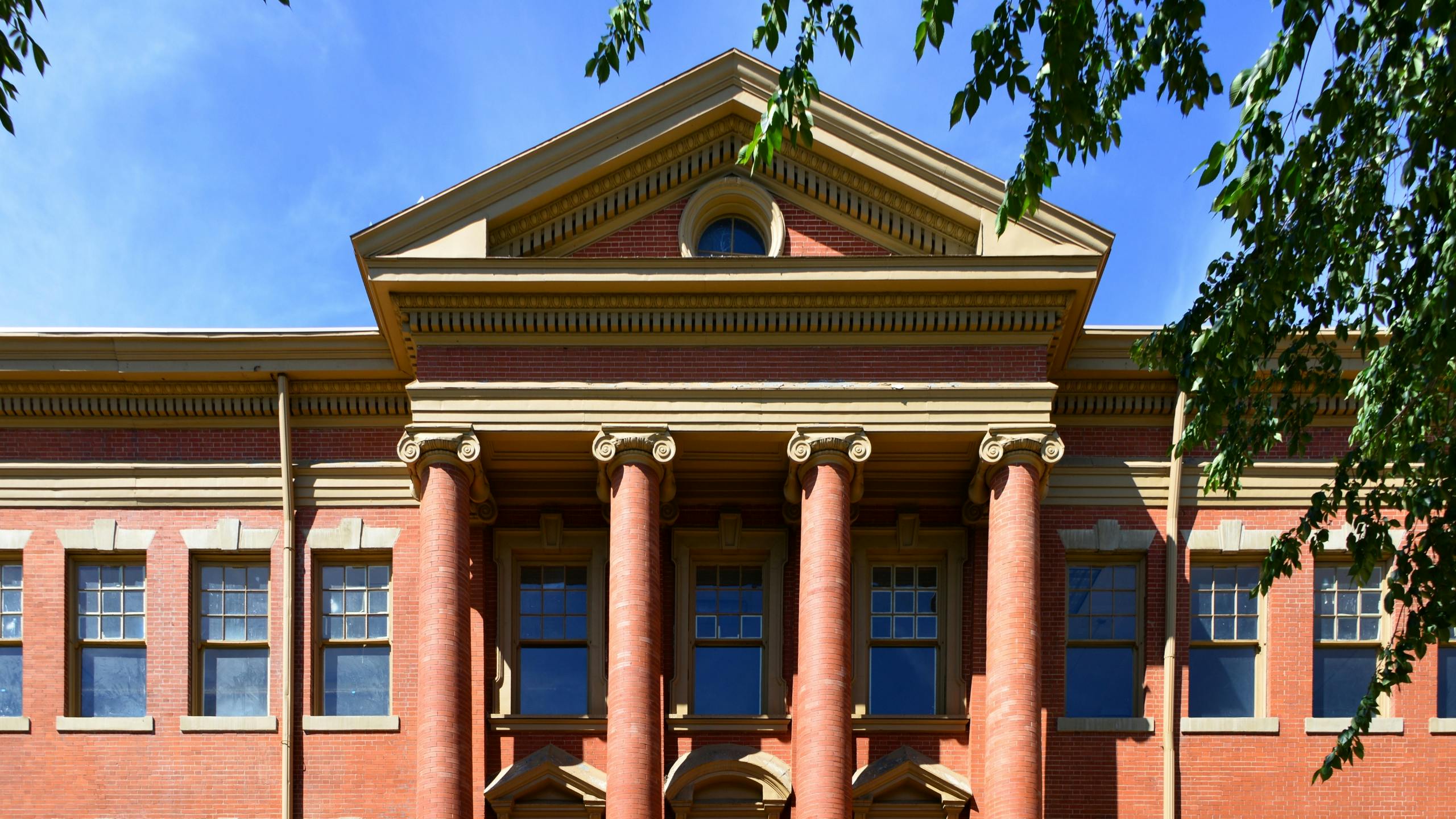 Exterior of the historic Evans School in Denver’s Golden Triangle, featuring red brick architecture and grand Ionic columns.