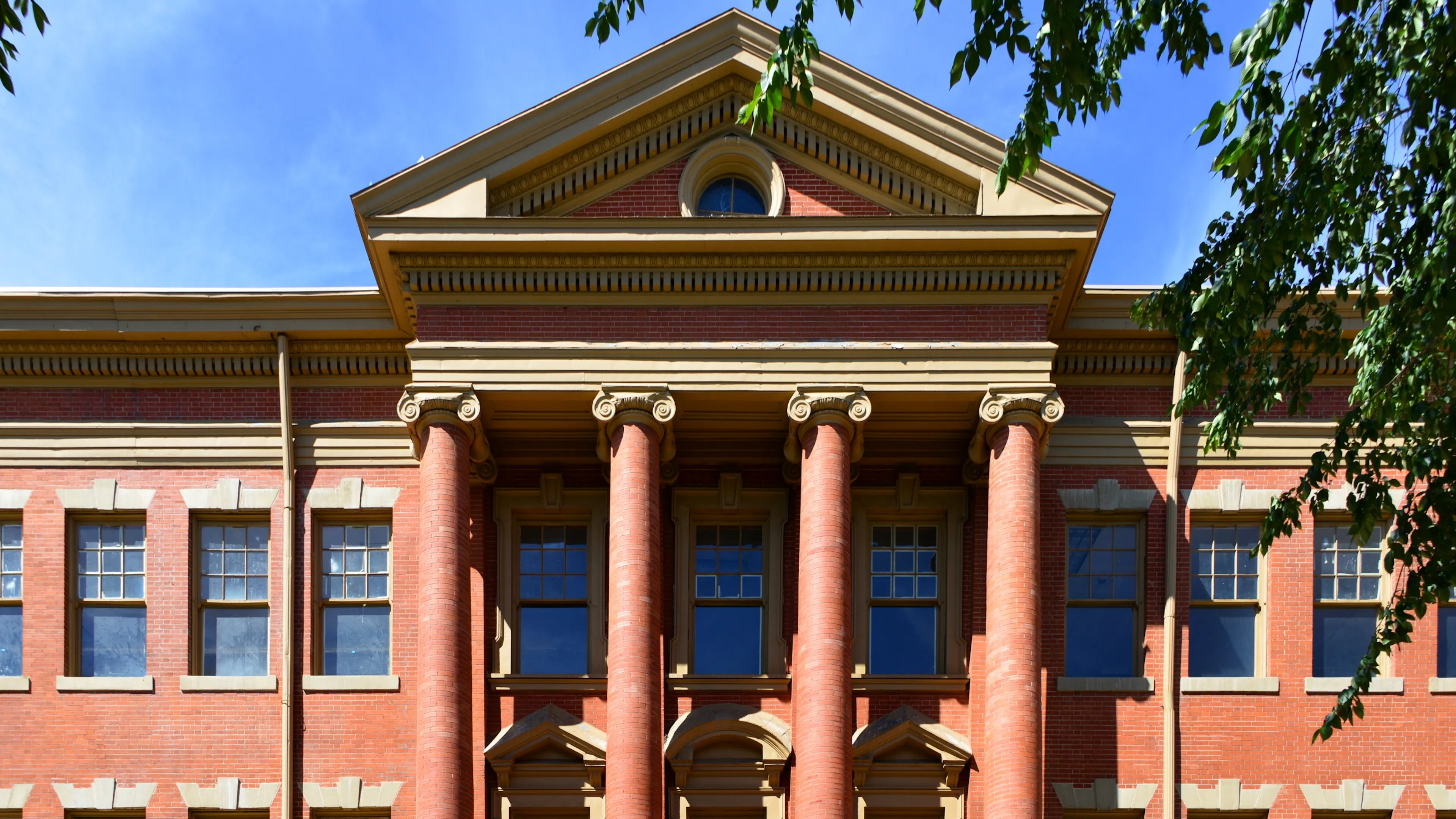 Exterior of the historic Evans School in Denver’s Golden Triangle, featuring red brick architecture and grand Ionic columns.