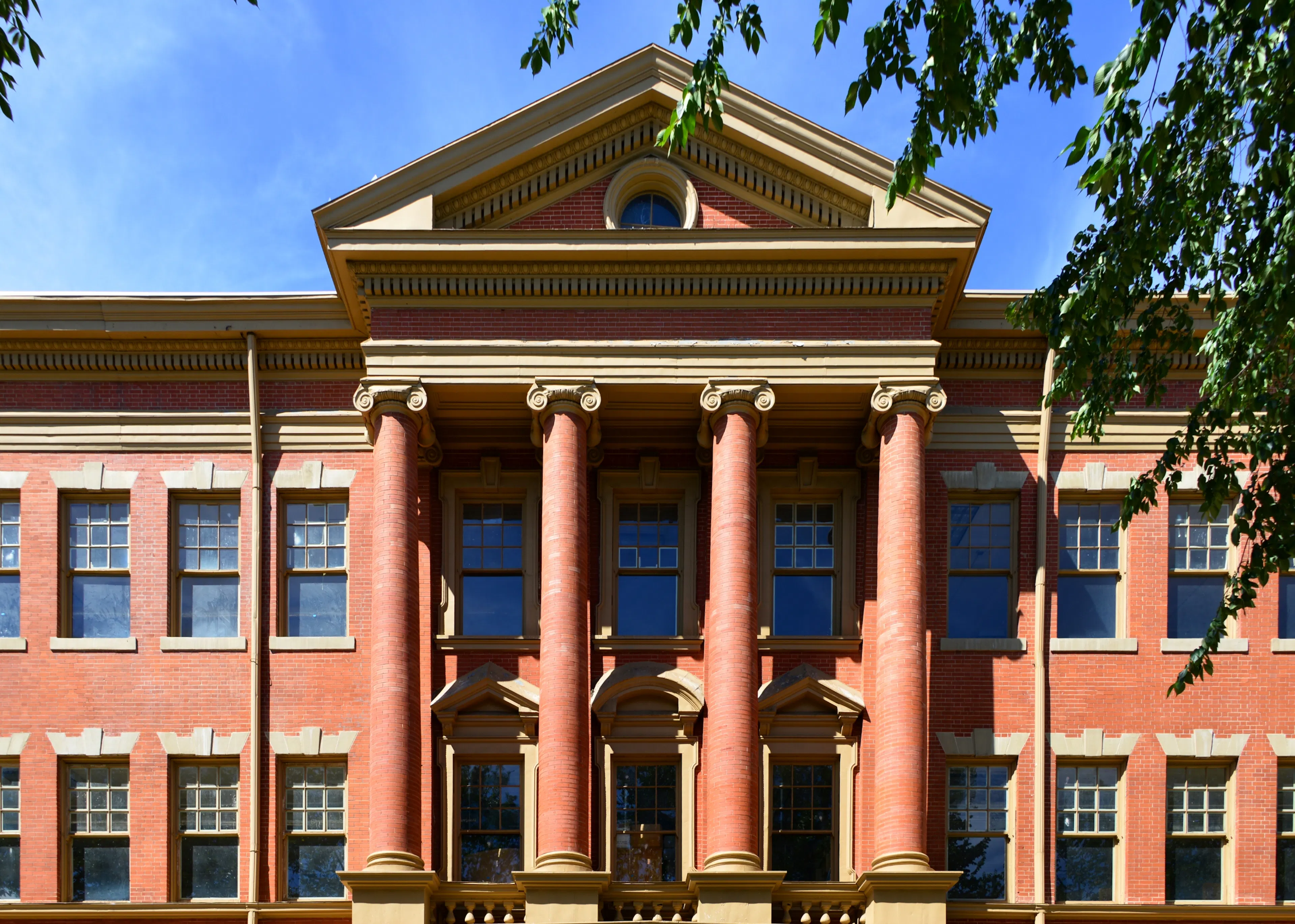 Exterior of the historic Evans School in Denver’s Golden Triangle, featuring red brick architecture and grand Ionic columns.
