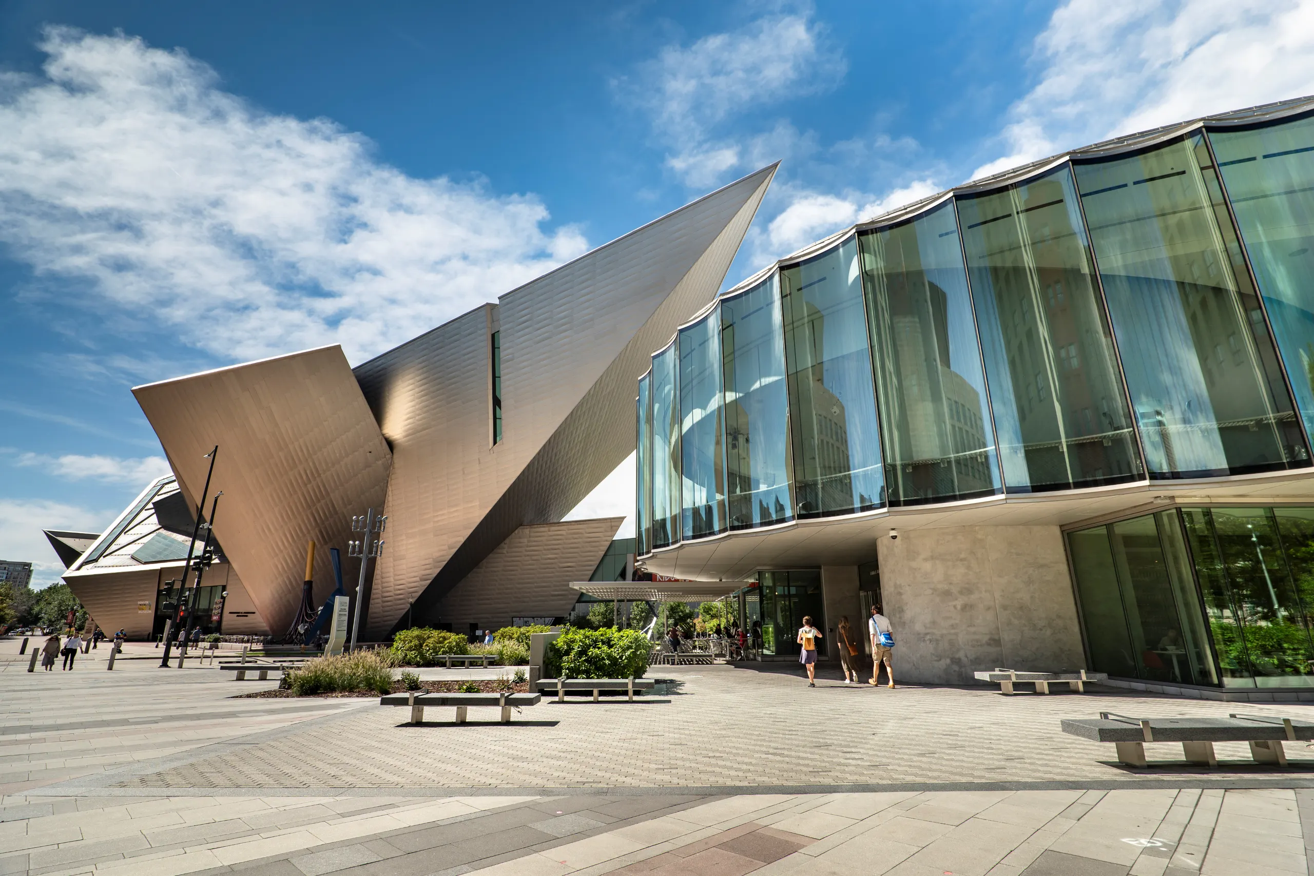 Exterior view of the Denver art museum featuring sharp angles and glass walls under a blue sky.