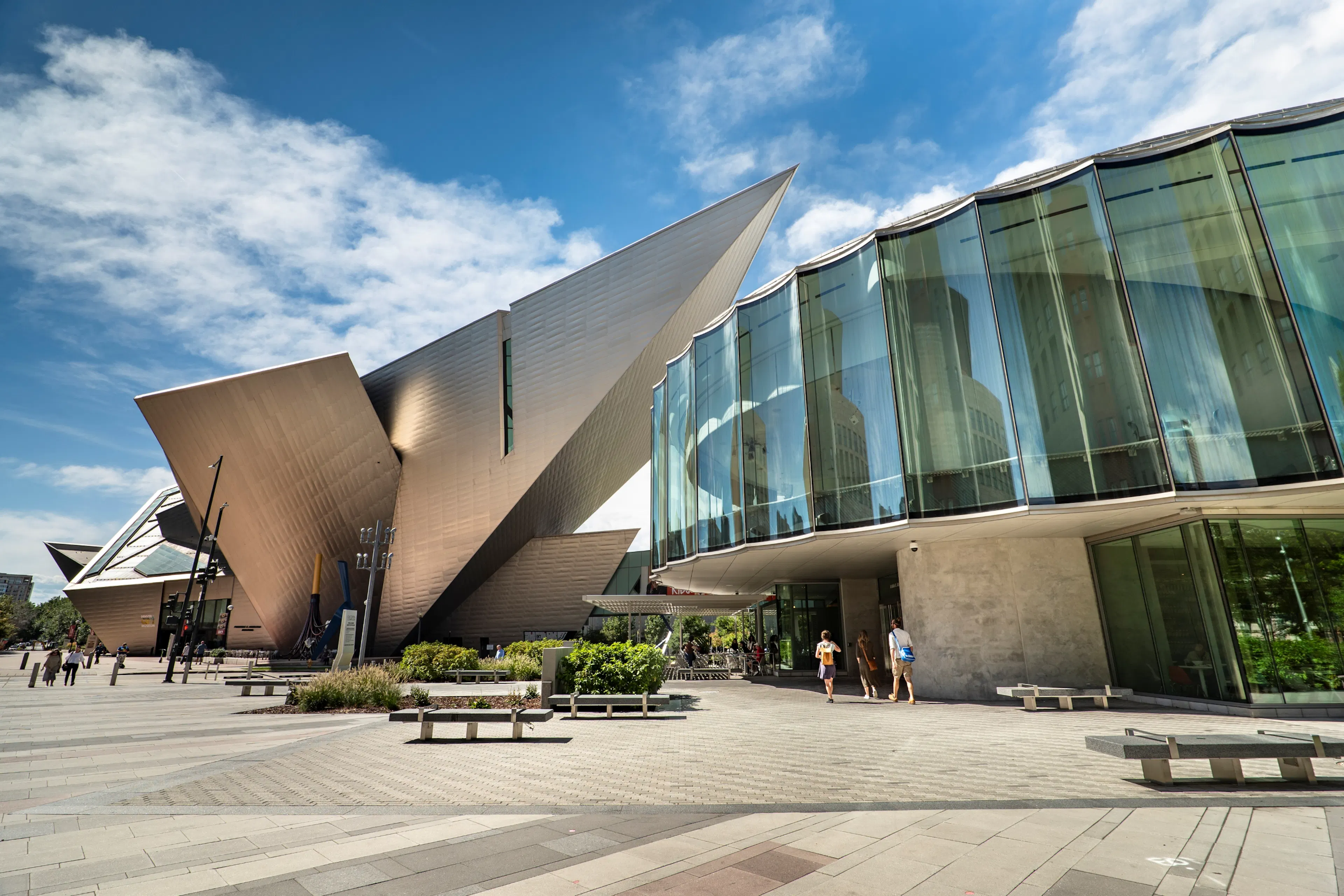 Exterior view of the Denver art museum featuring sharp angles and glass walls under a blue sky.