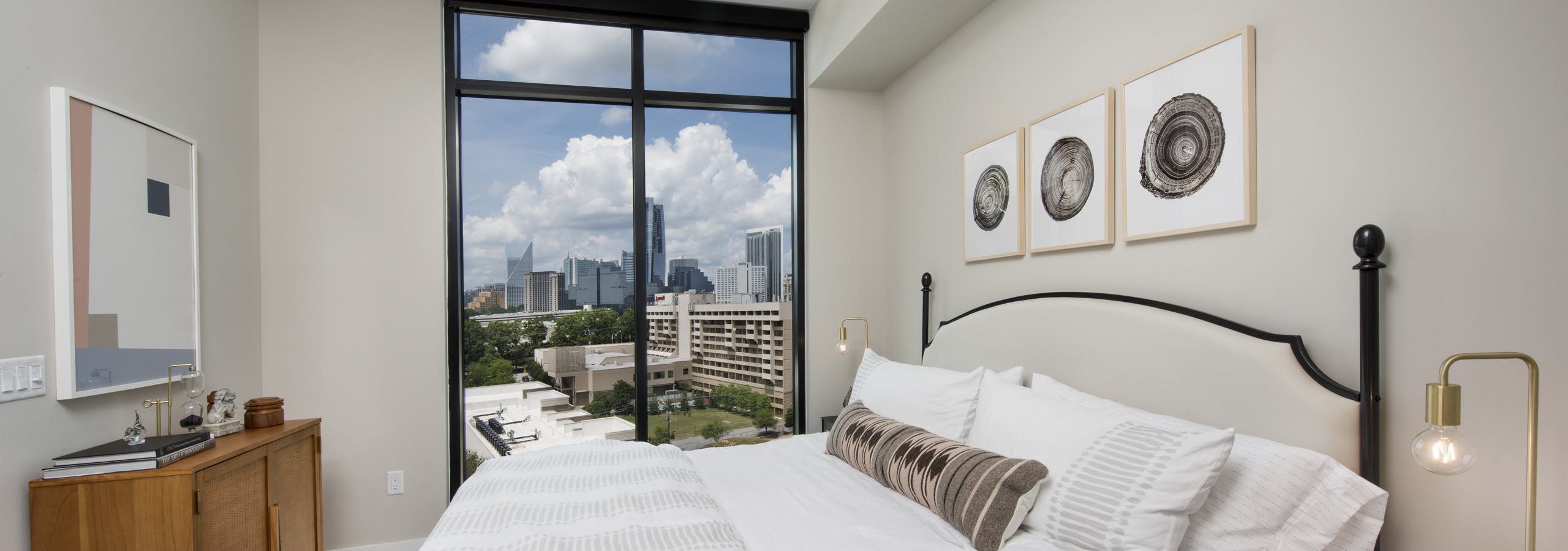 AMLI Lenox bedroom with floor to ceiling windows and a bed with a white comforter and bedside nightstands with lamps