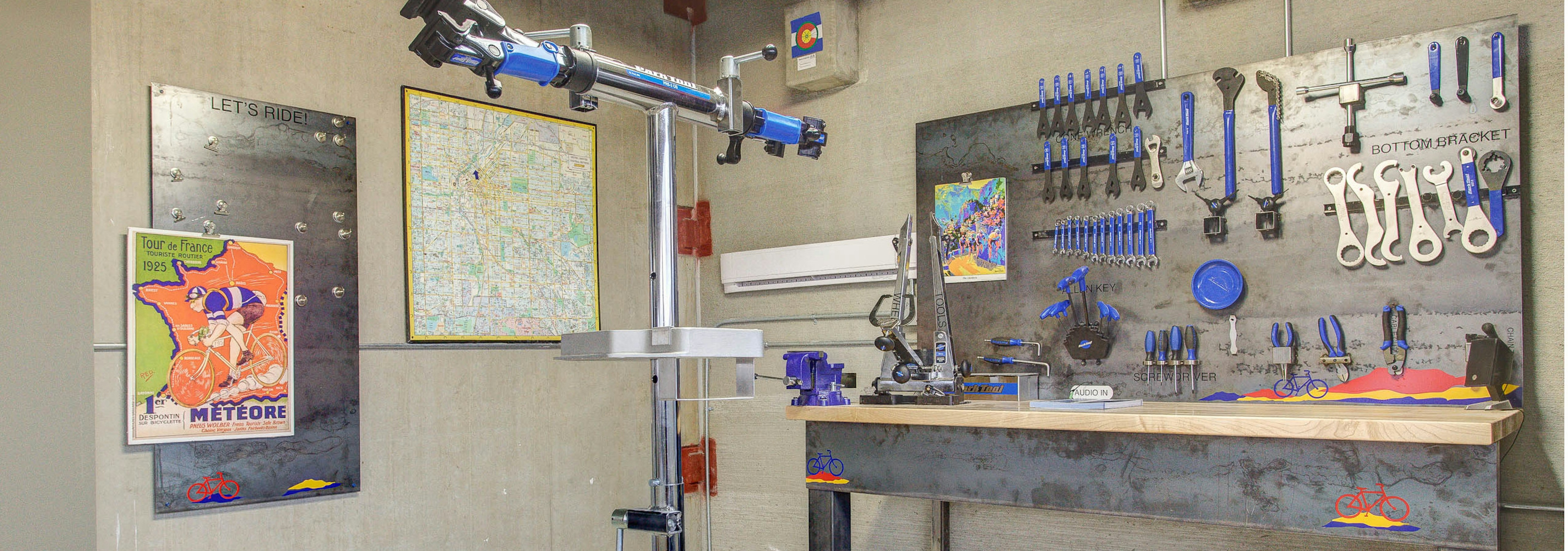 Interior of the bike repair room at AMLI Riverfront Park apartments with a work bench and tools and steel bike repair stand 