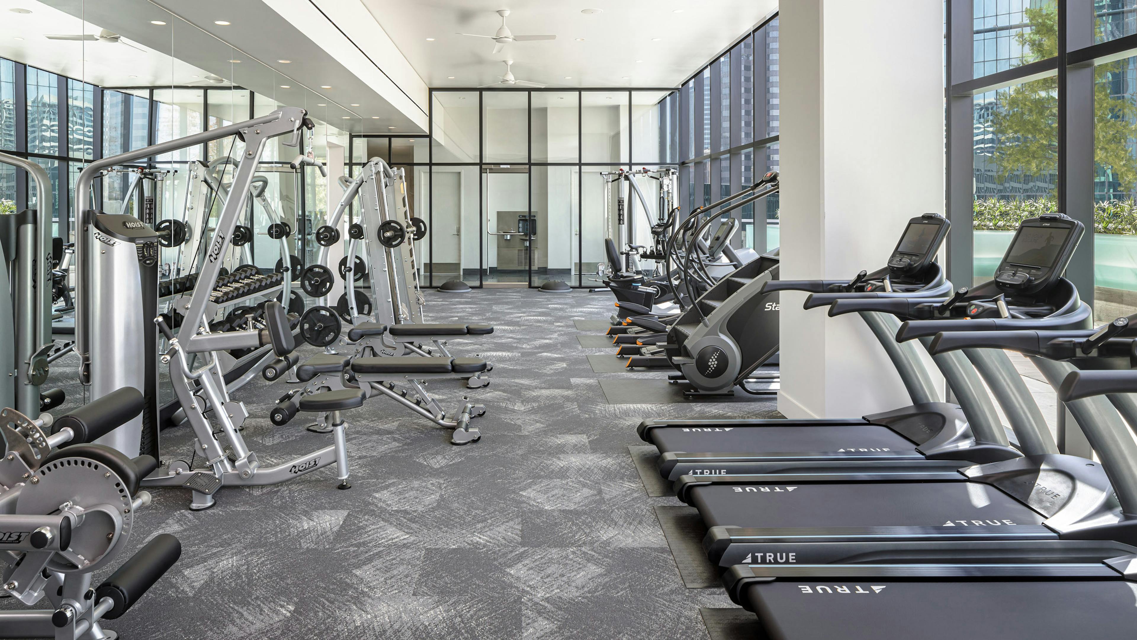 Interior view of fitness center at AMLI Fountain Place apartment building with tread mills, weight machines and large windows