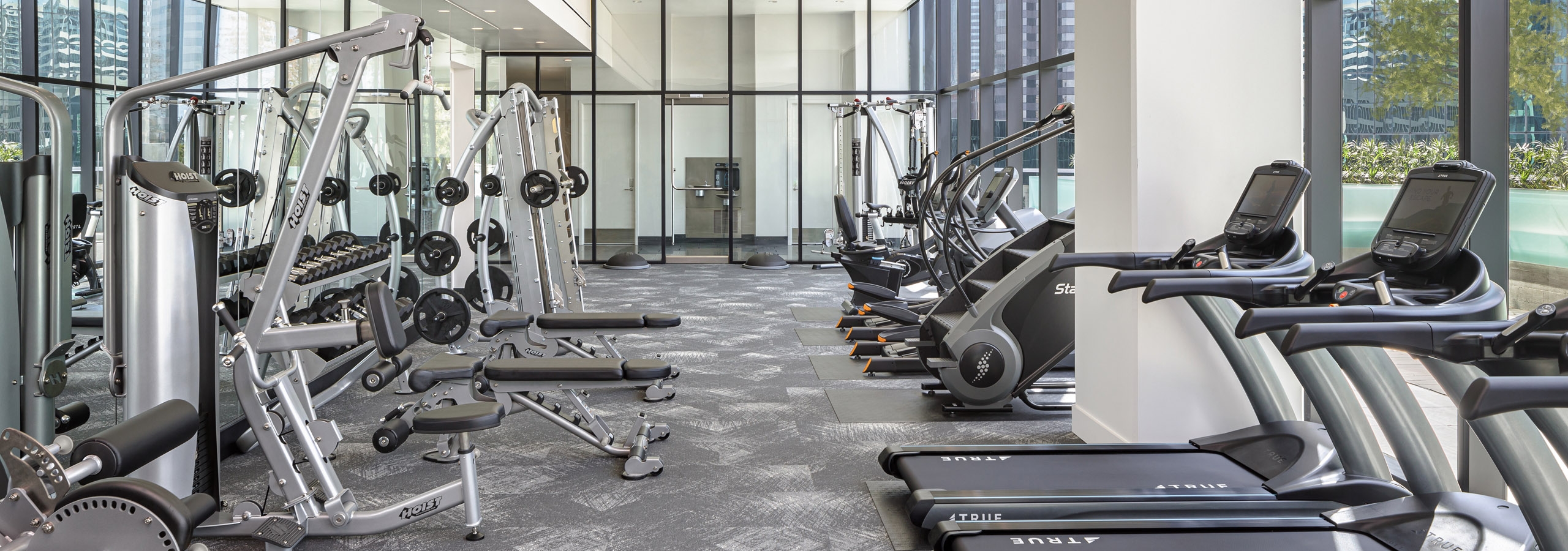 Interior view of fitness center at AMLI Fountain Place apartment building with tread mills, weight machines and large windows