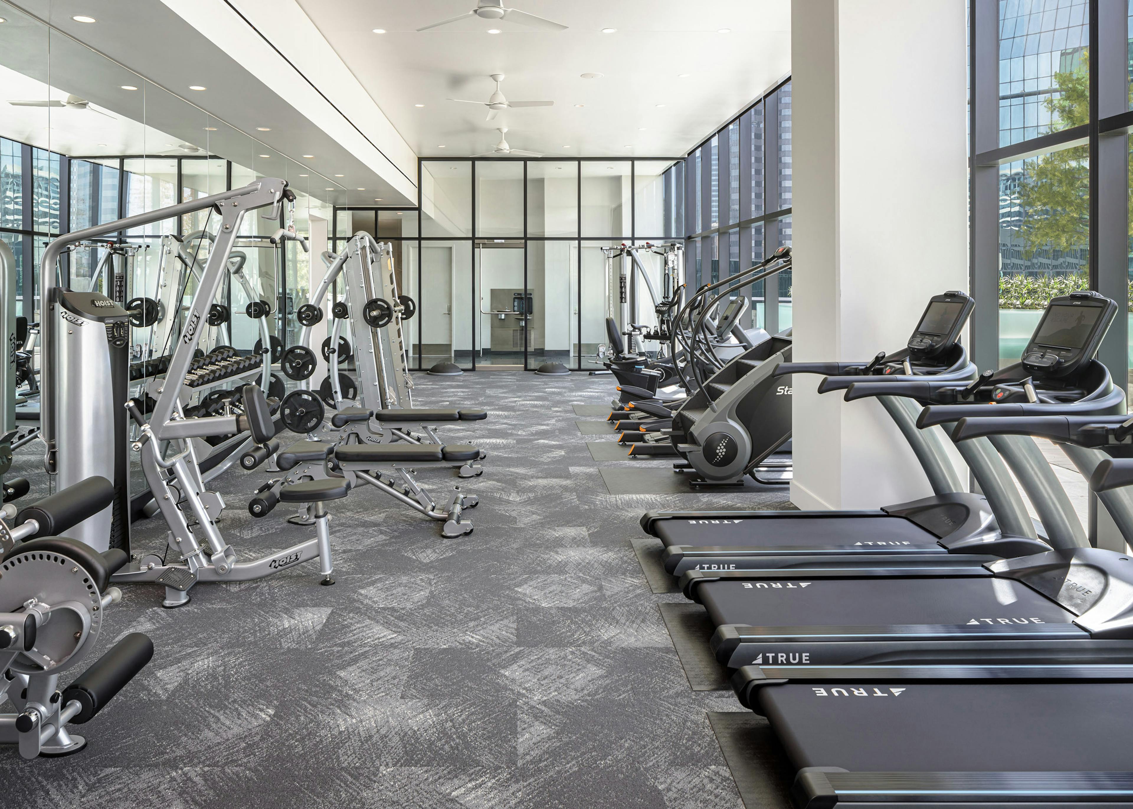 Interior view of fitness center at AMLI Fountain Place apartment building with tread mills, weight machines and large windows
