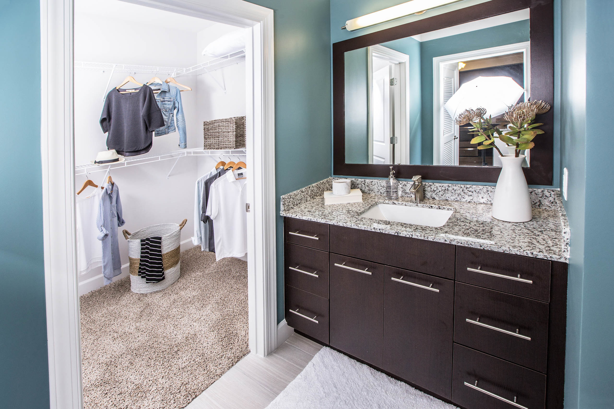 Interior view of a bathroom at AMLI Joya apartment with double sink vanity, large mirror on wall and granite counters
