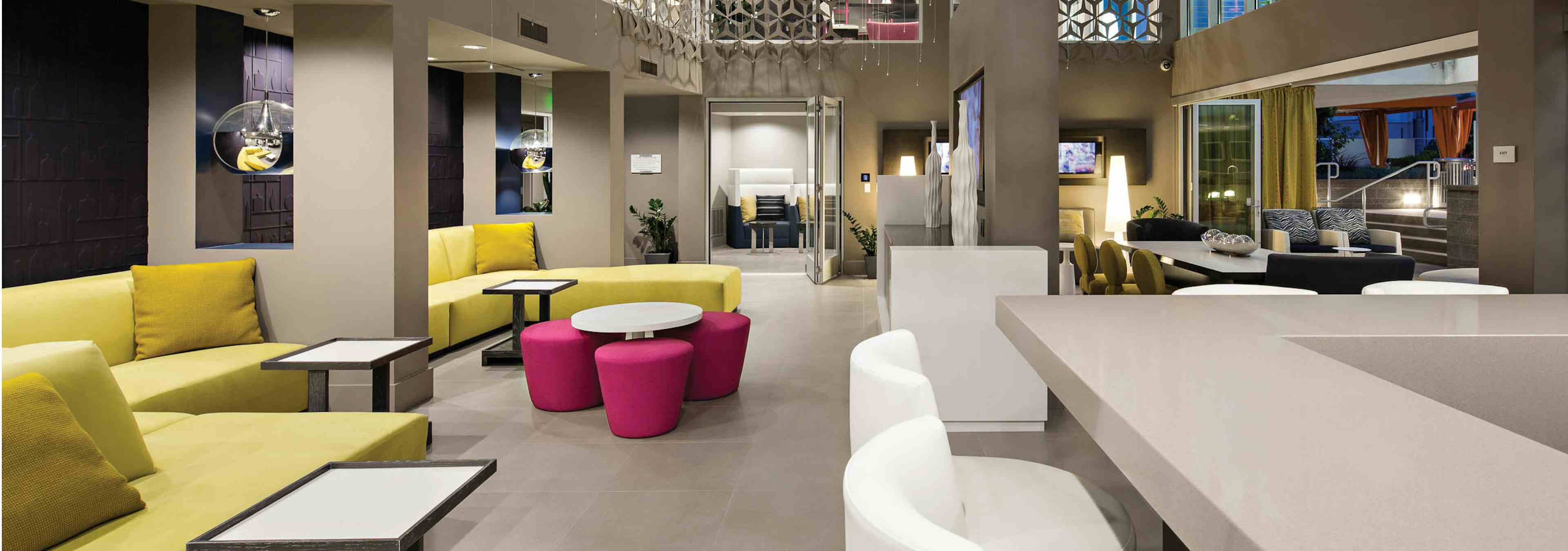 Interior of clubhouse with plentiful seating and glass accordion doors overlooking pool area at AMLI Lex on Orange apartments