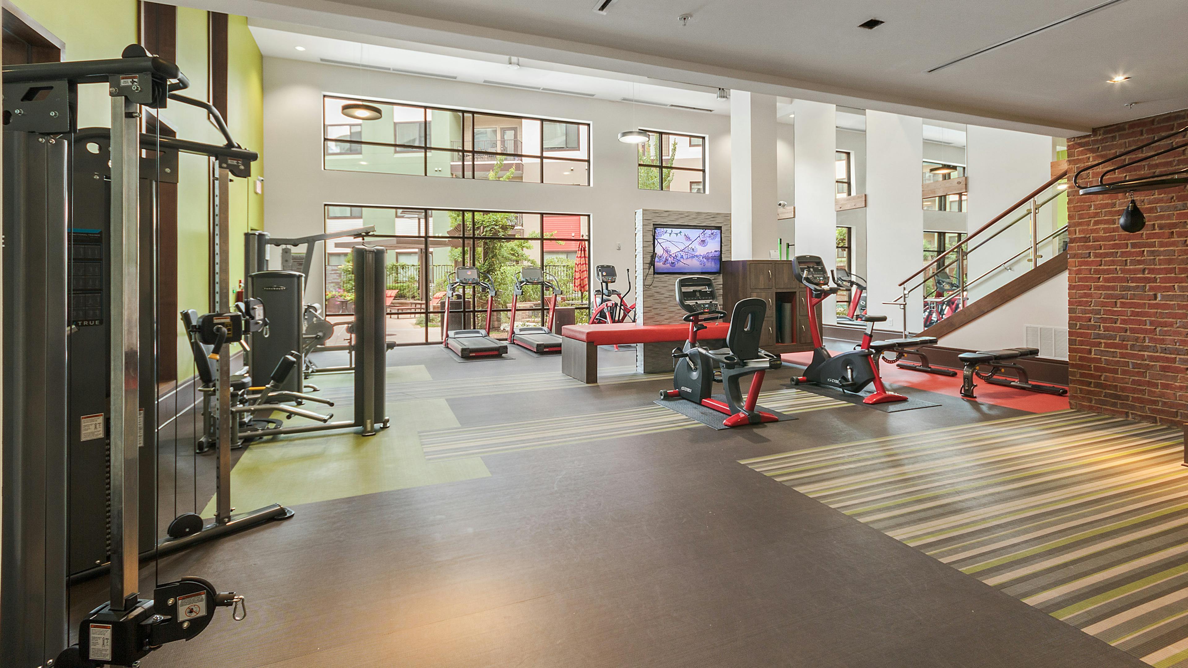 Interior of the fitness center at AMLI Ponce Park apartments with multiple treadmills and exercise bike and weight machines