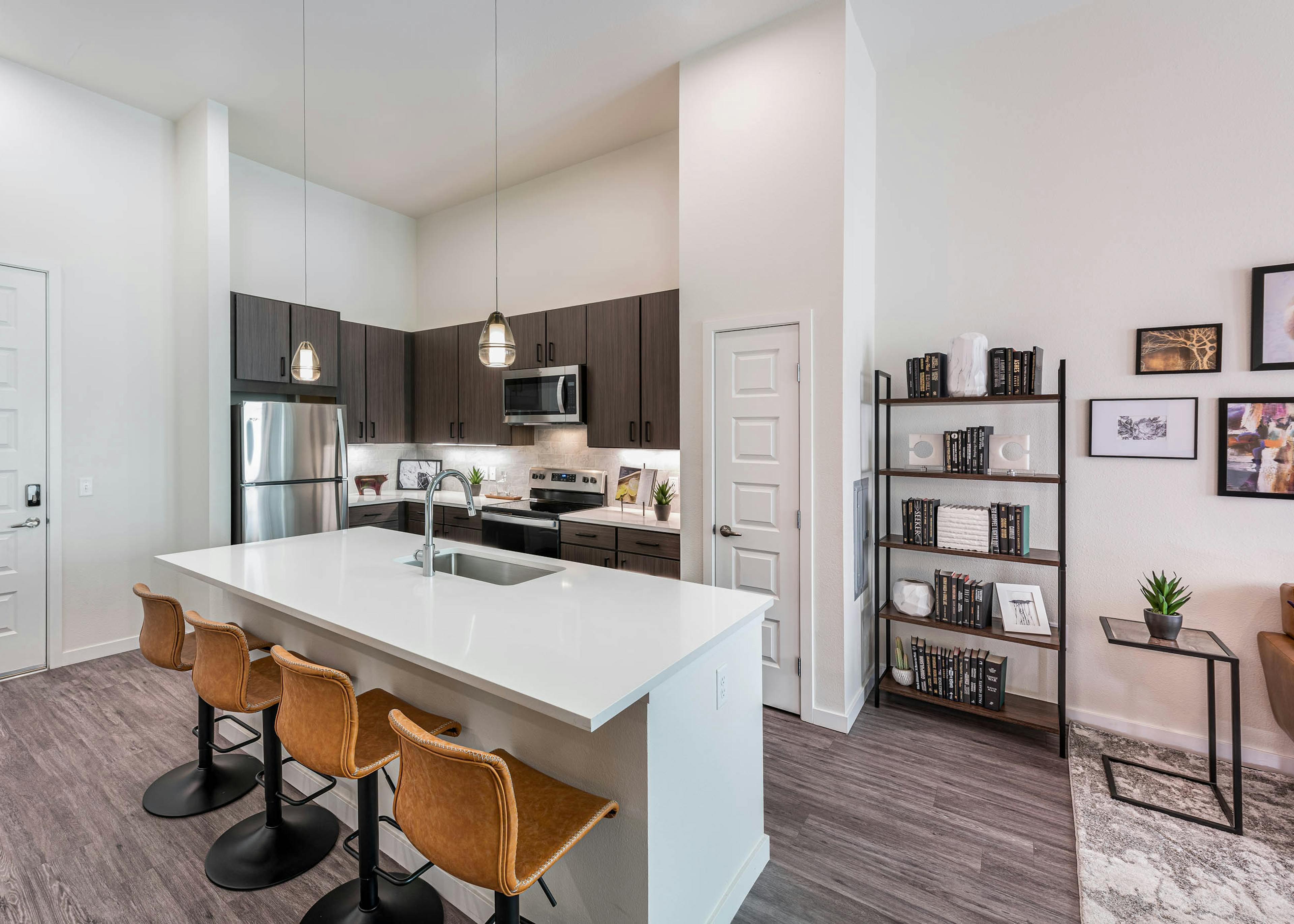 AMLI Art District apartment kitchen with an island and leather bar stools and brown cabinets and stainless appliances
