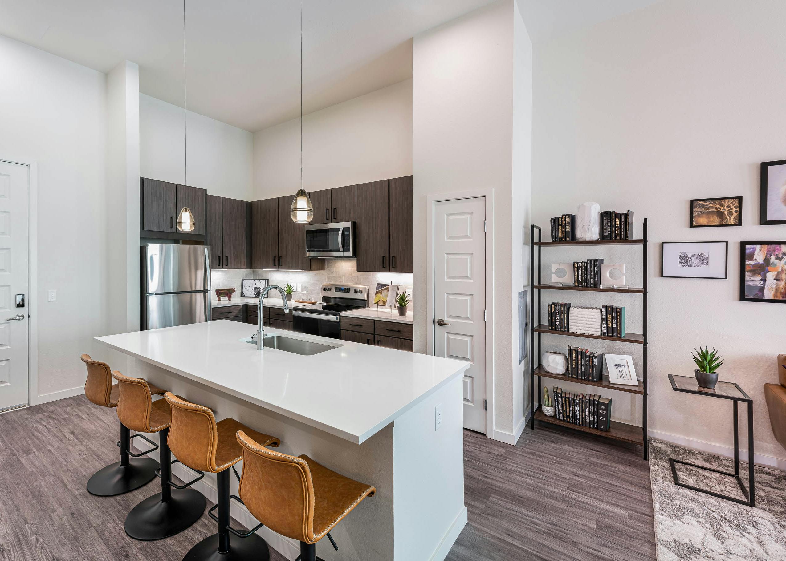AMLI Art District apartment kitchen with an island and leather bar stools and brown cabinets and stainless appliances