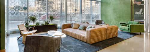 AMLI on 2nd leasing office with floor to ceiling windows and green walls with two patterned orange sofas and various chairs