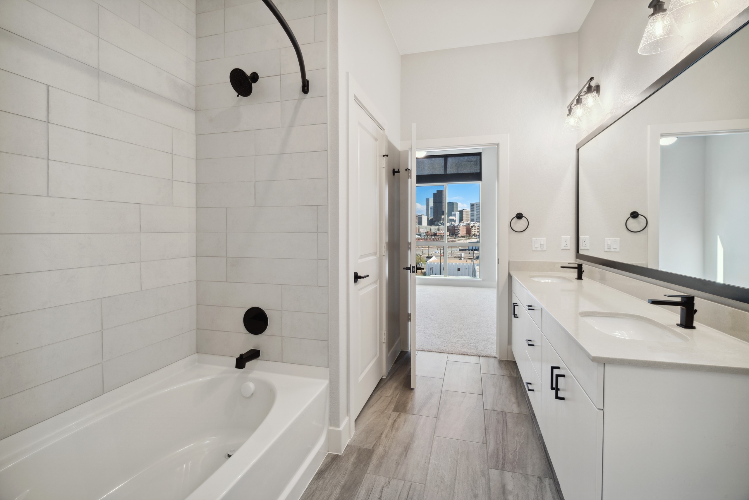 AMLI RiNo bathroom with white garden tub and tile surround and white cabinets and countertops and black finish hardware 