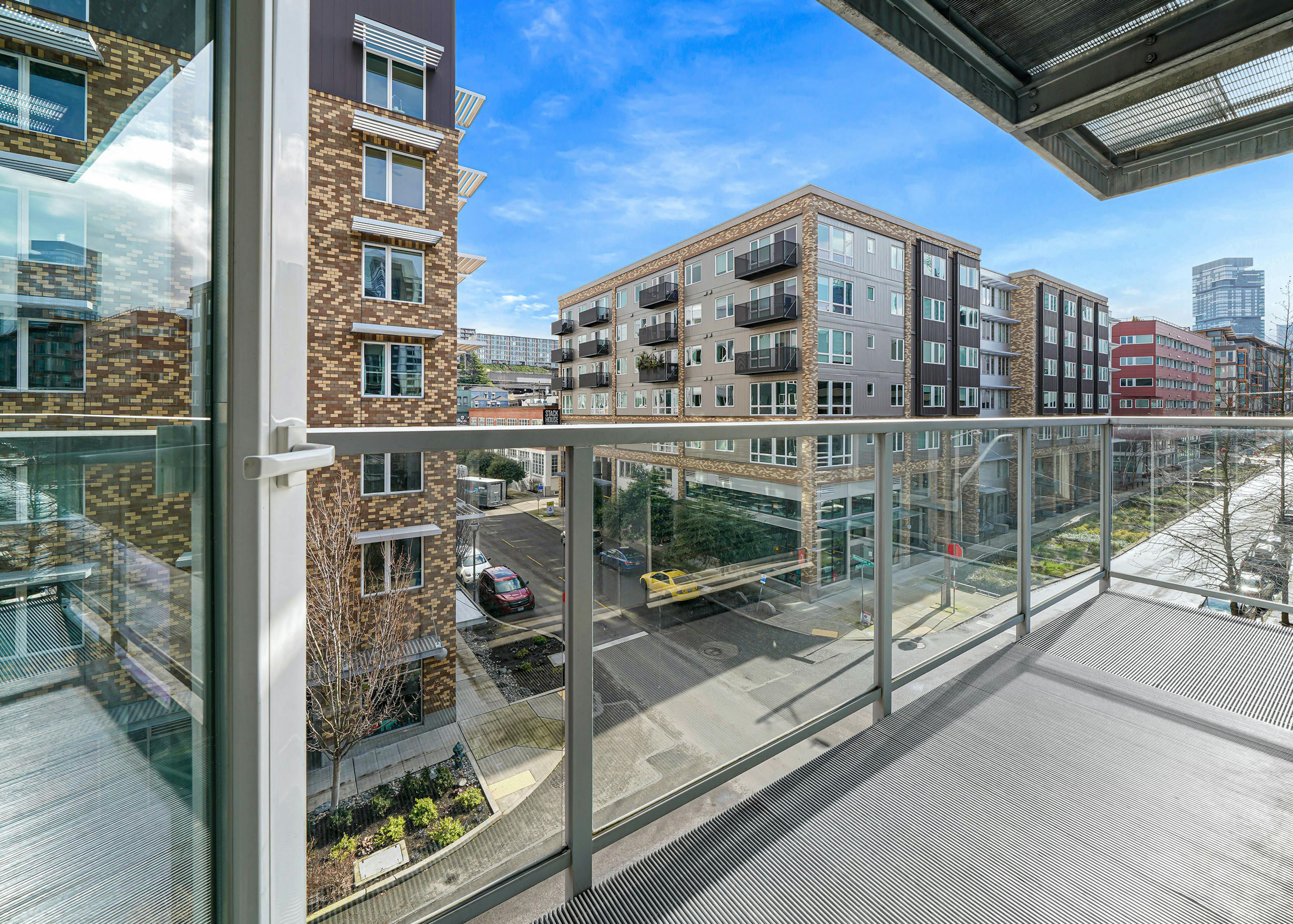 A large apartment balcony at AMLI 535 with glass door with views of South Lake Union with cars on the street and blue sky 