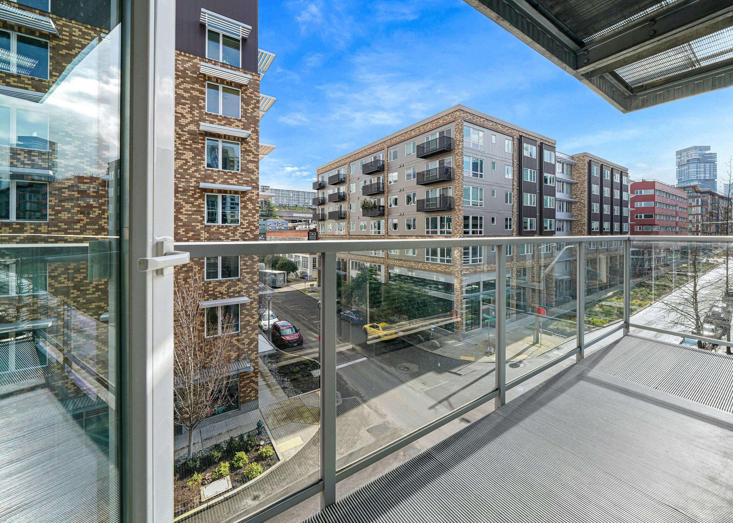 A large apartment balcony at AMLI 535 with glass door with views of South Lake Union with cars on the street and blue sky