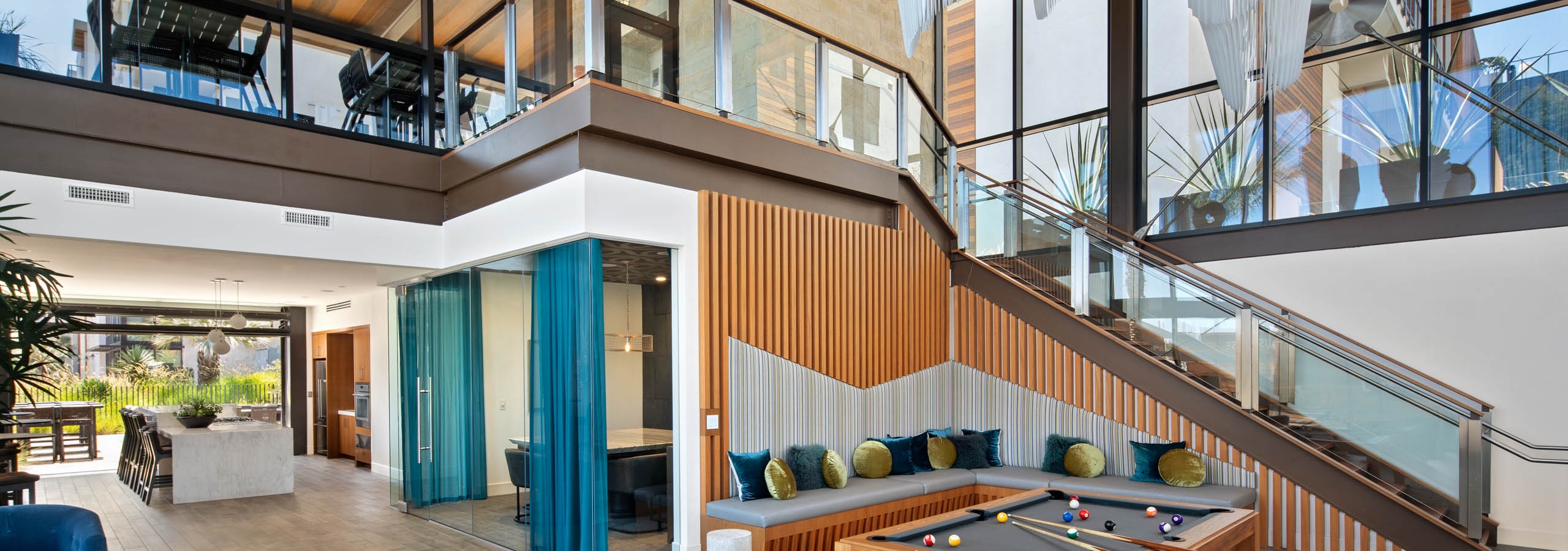 Two story Jewel building with pool table and seating and white modern chandeliers at AMLI Marina Del Rey apartments
