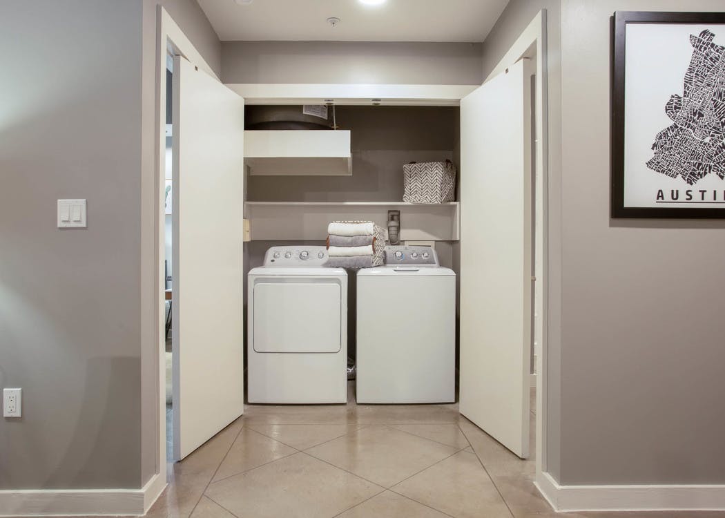 Interior view of in unit laundry machines at AMLI Downtown which are tucked away in a closet with folding doors