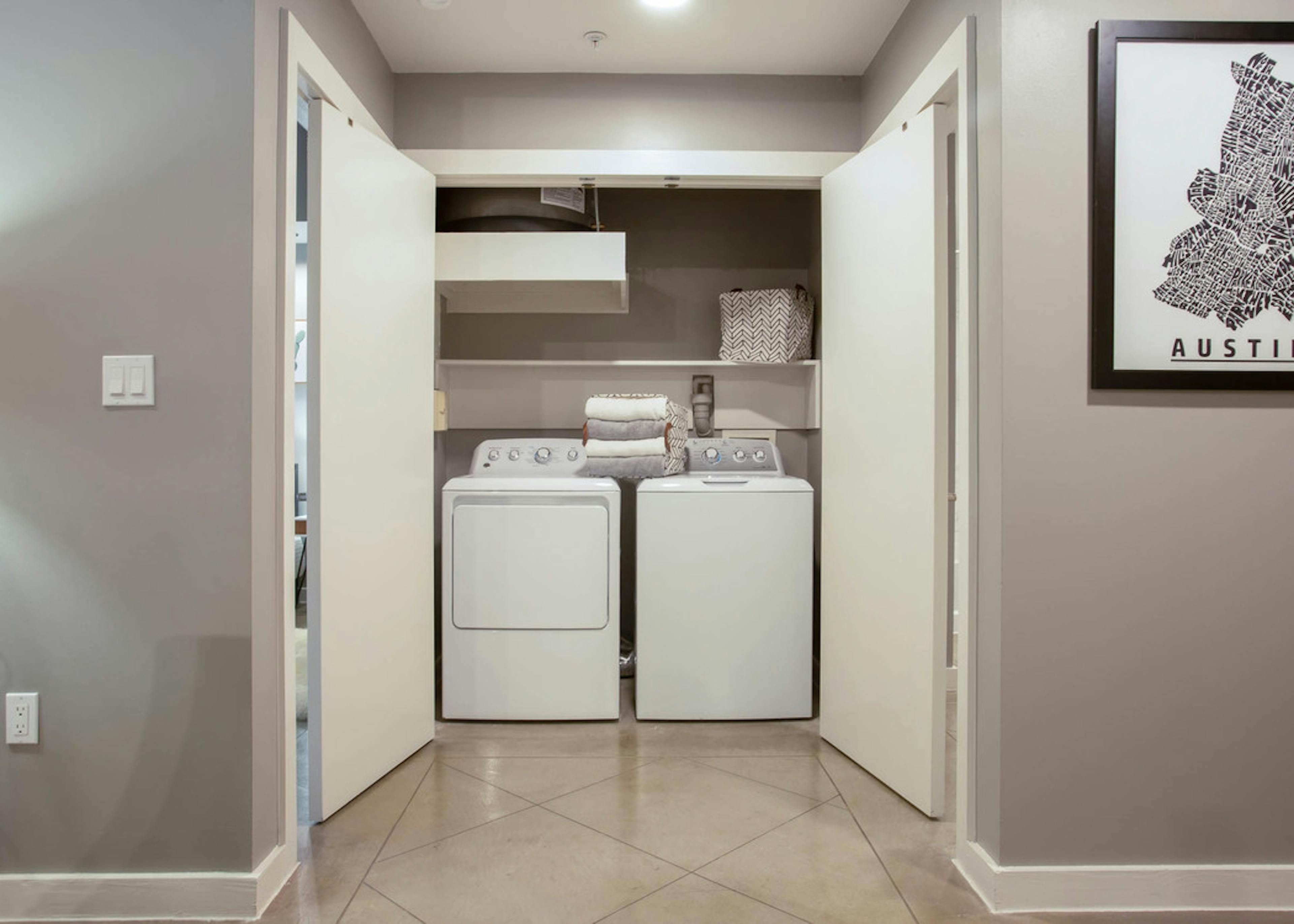 Interior view of in unit laundry machines at AMLI Downtown which are tucked away in a closet with folding doors