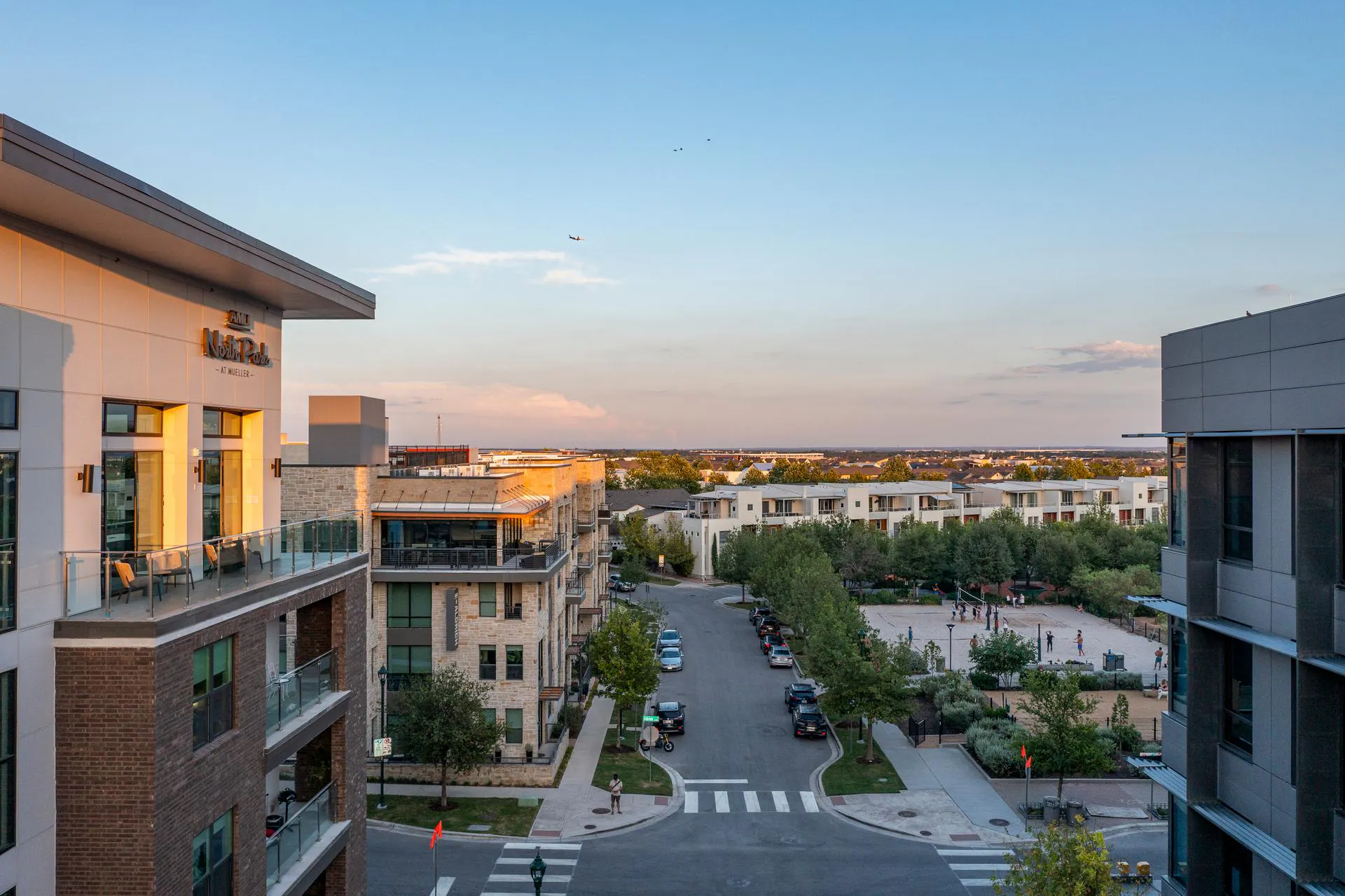 A sunset view of a street in Mueller with tree-lined streets and luxury apartment buildings
