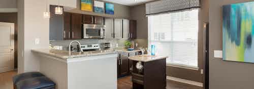 Interior of kitchen at AMLI Memorial Heights with stainless steel appliances and granite countertops and dark wood cabinets