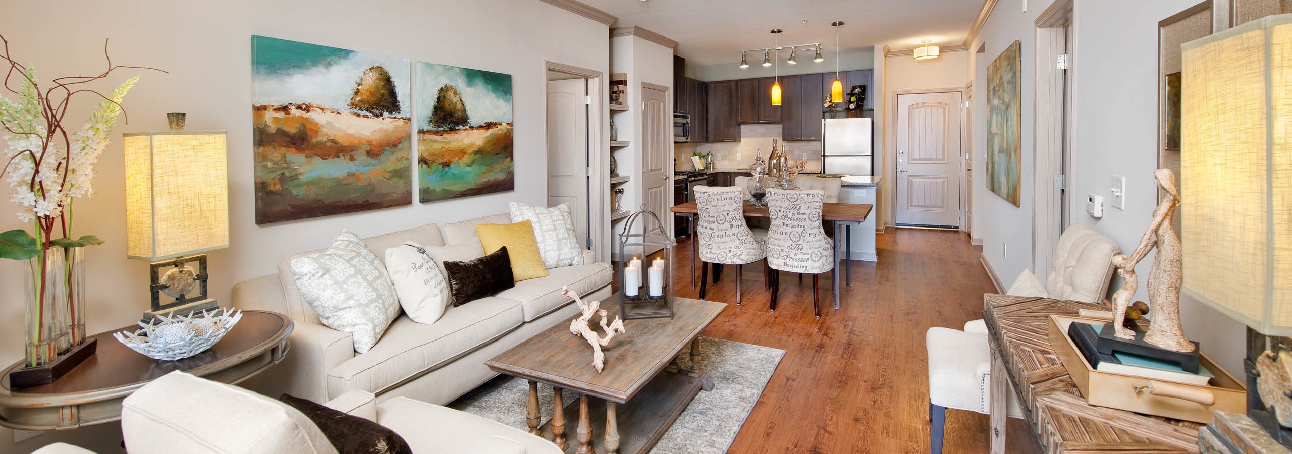 Close up of AMLI North Point living room with chestnut colored wood floors connecting to a dining area and kitchen
