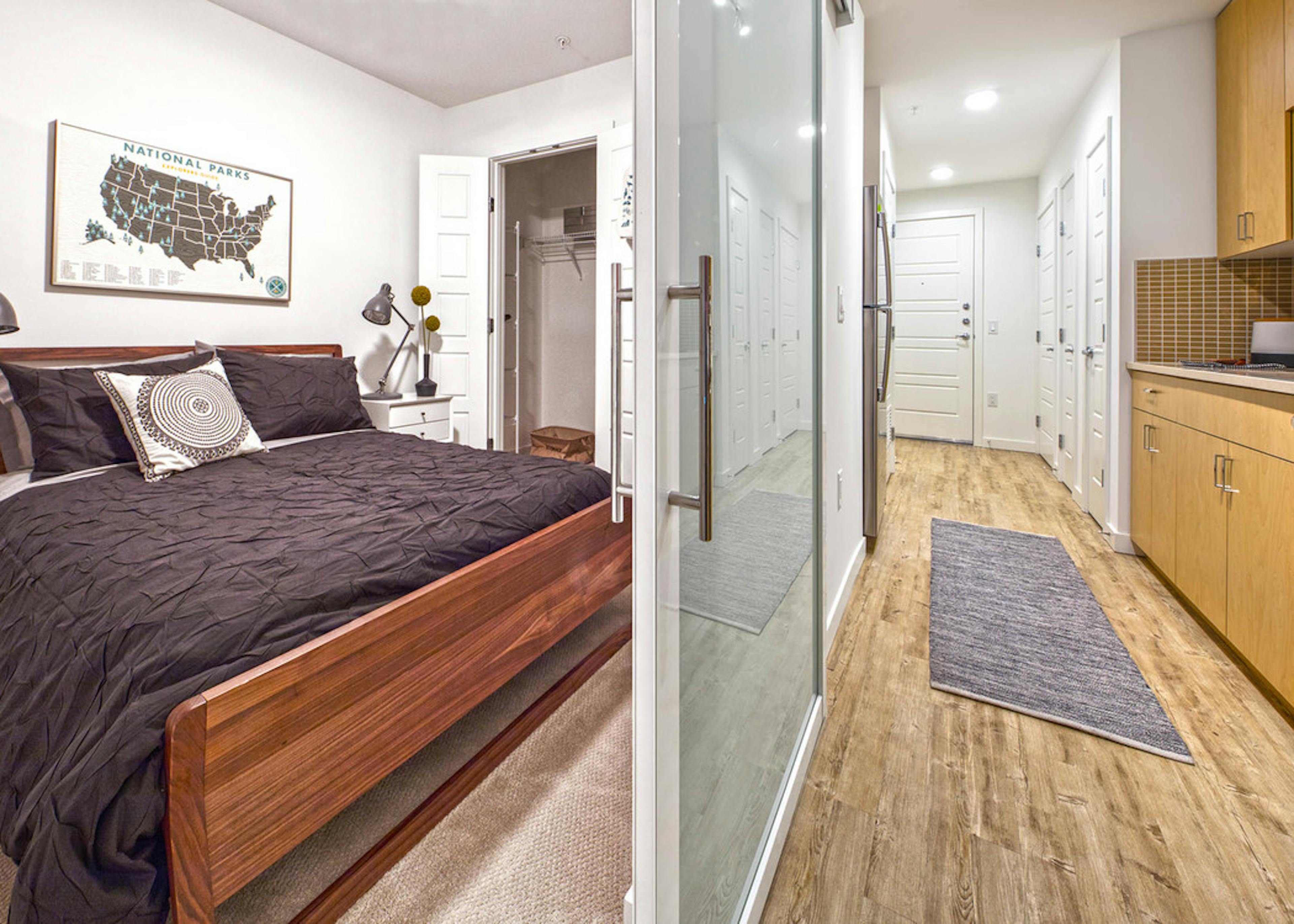 Interior apartment at AMLI Wallingford with view of bedroom with full size bed and walk through kitchen 