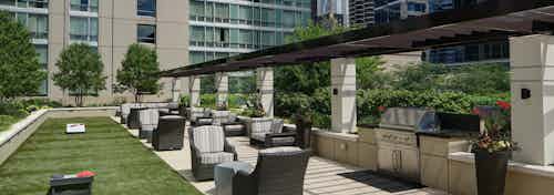 Rooftop grill area and garden at AMLI River North apartment community with surrounding outdoor seating and bright foliage