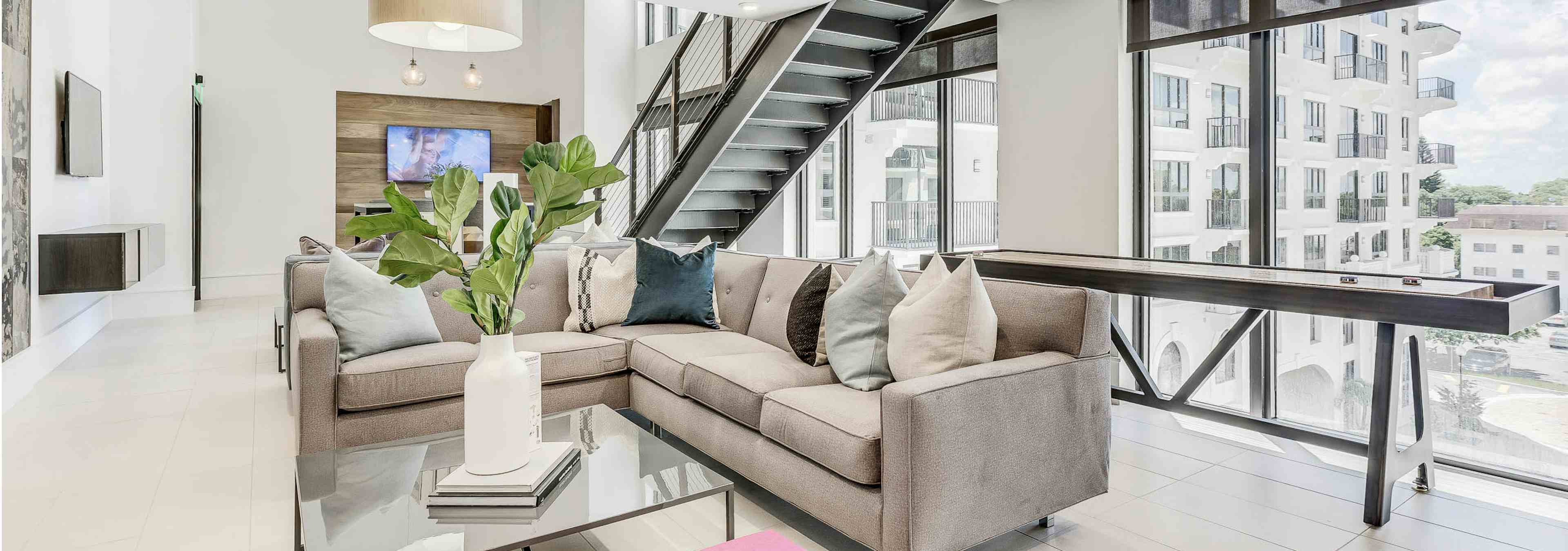 First floor interior view of the AMLI Joya two story game room with two sectional sofas and shuffleboard table