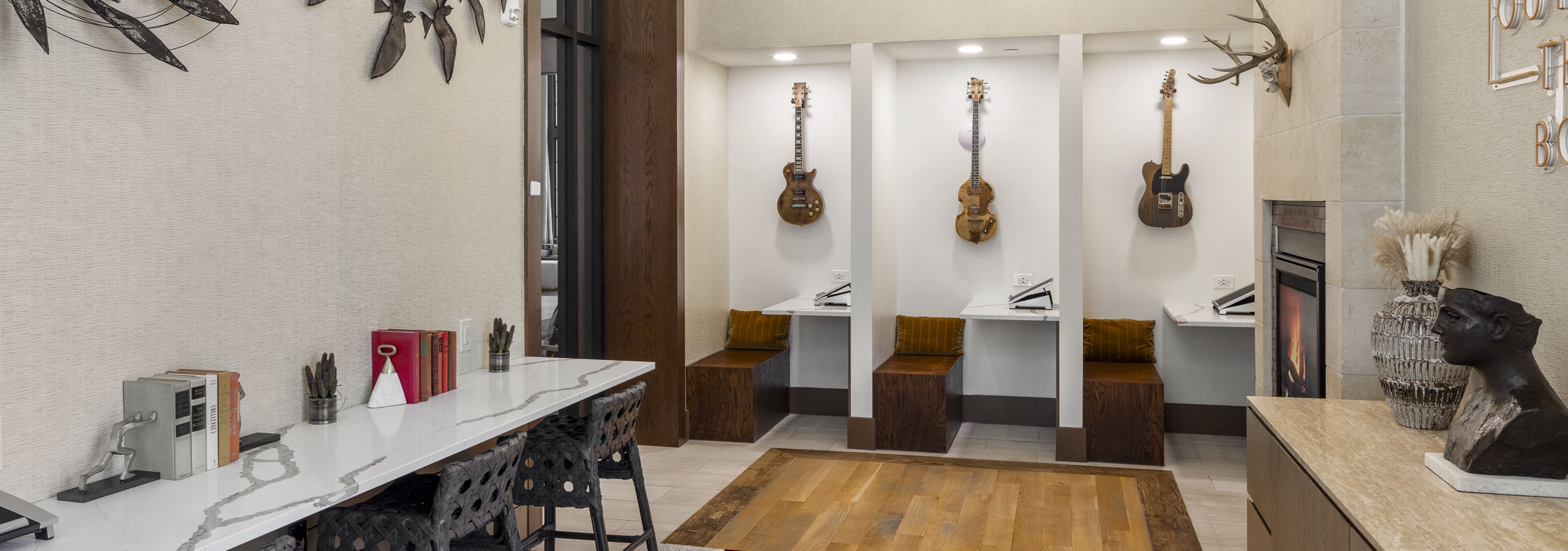 Business Center at AMLI Lakeline with built in work cubicles with hanging guitars and white marble desk top with 3 chairs
