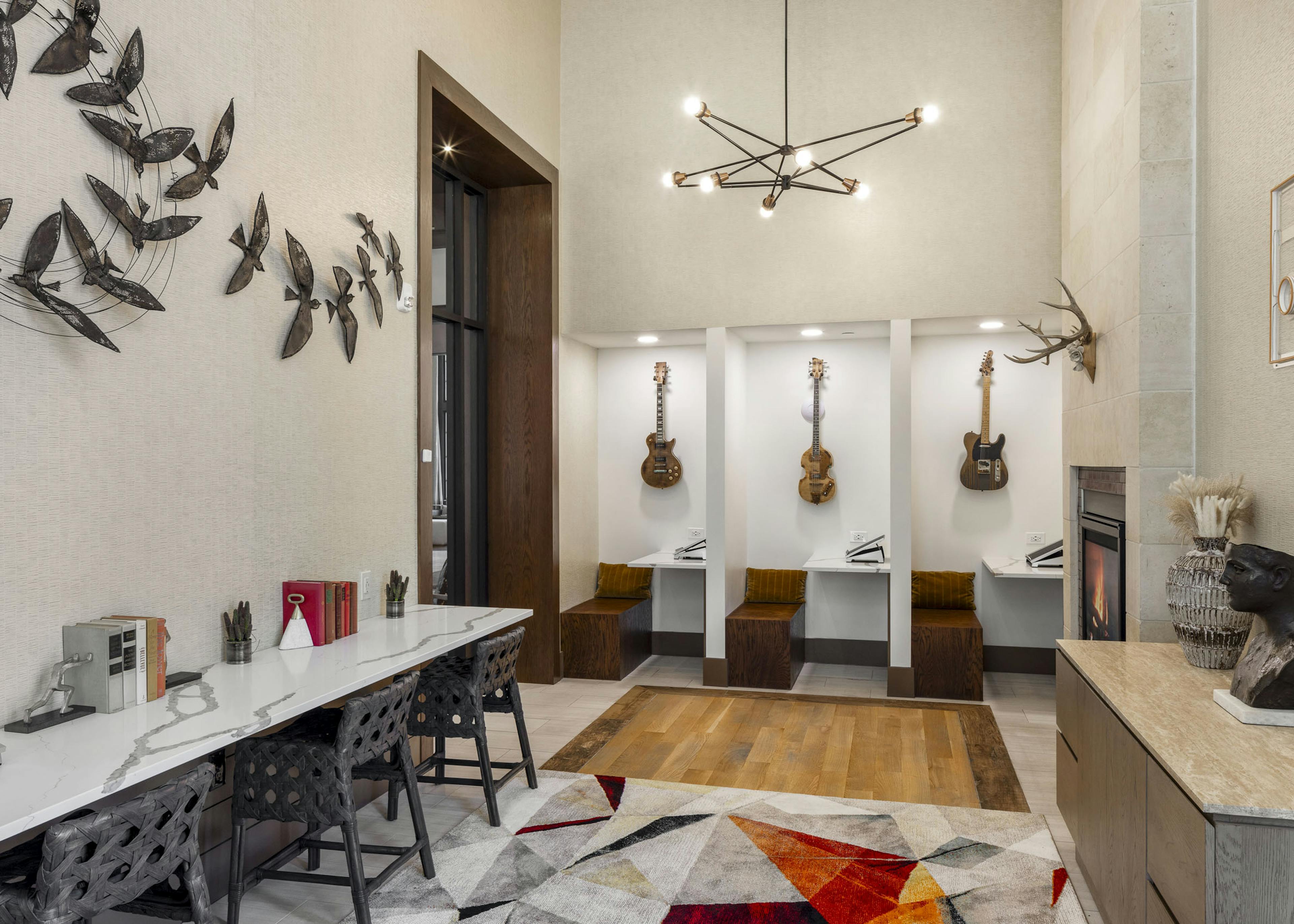 Business Center at AMLI Lakeline with built in work cubicles with hanging guitars and white marble desk top with 3 chairs 