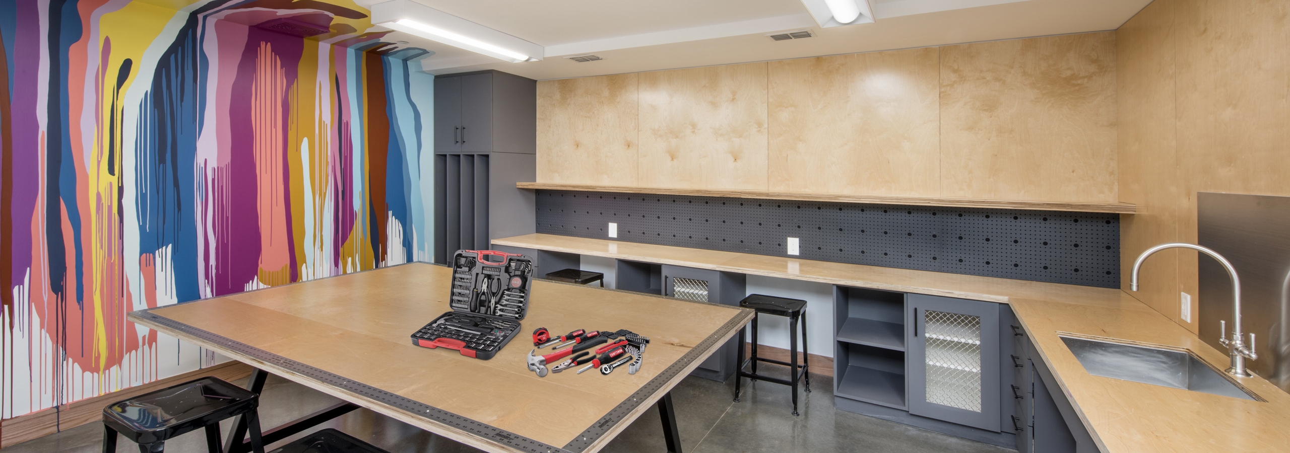 DIY maker space at AMLI Lenox with colorful painted wall and tools and sink as well as work areas for residents to create